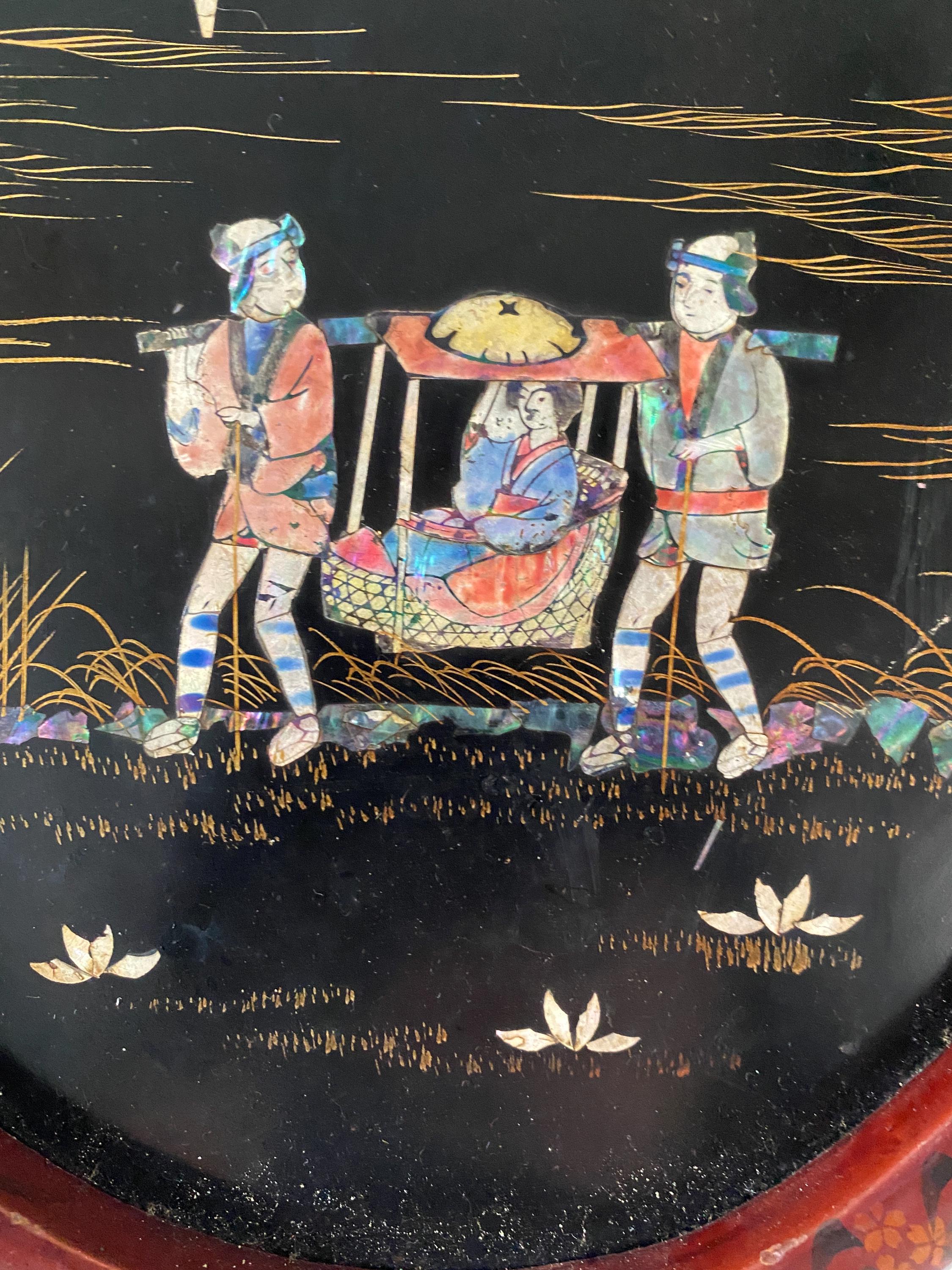 Detail of a decorative panel with a design of a woman being carried in a sedan chair by two male figures on a black background