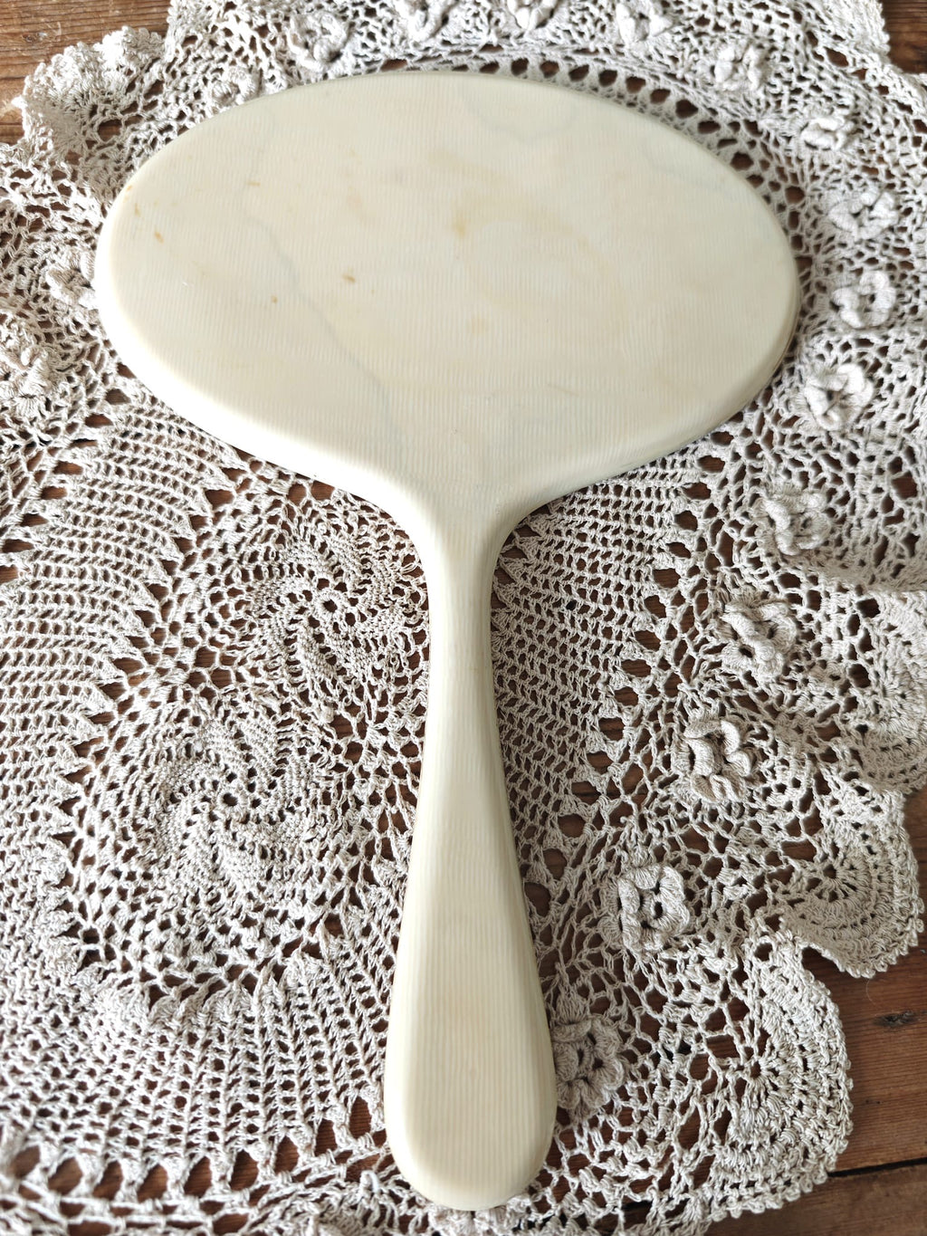 White hand mirror on a lace doily