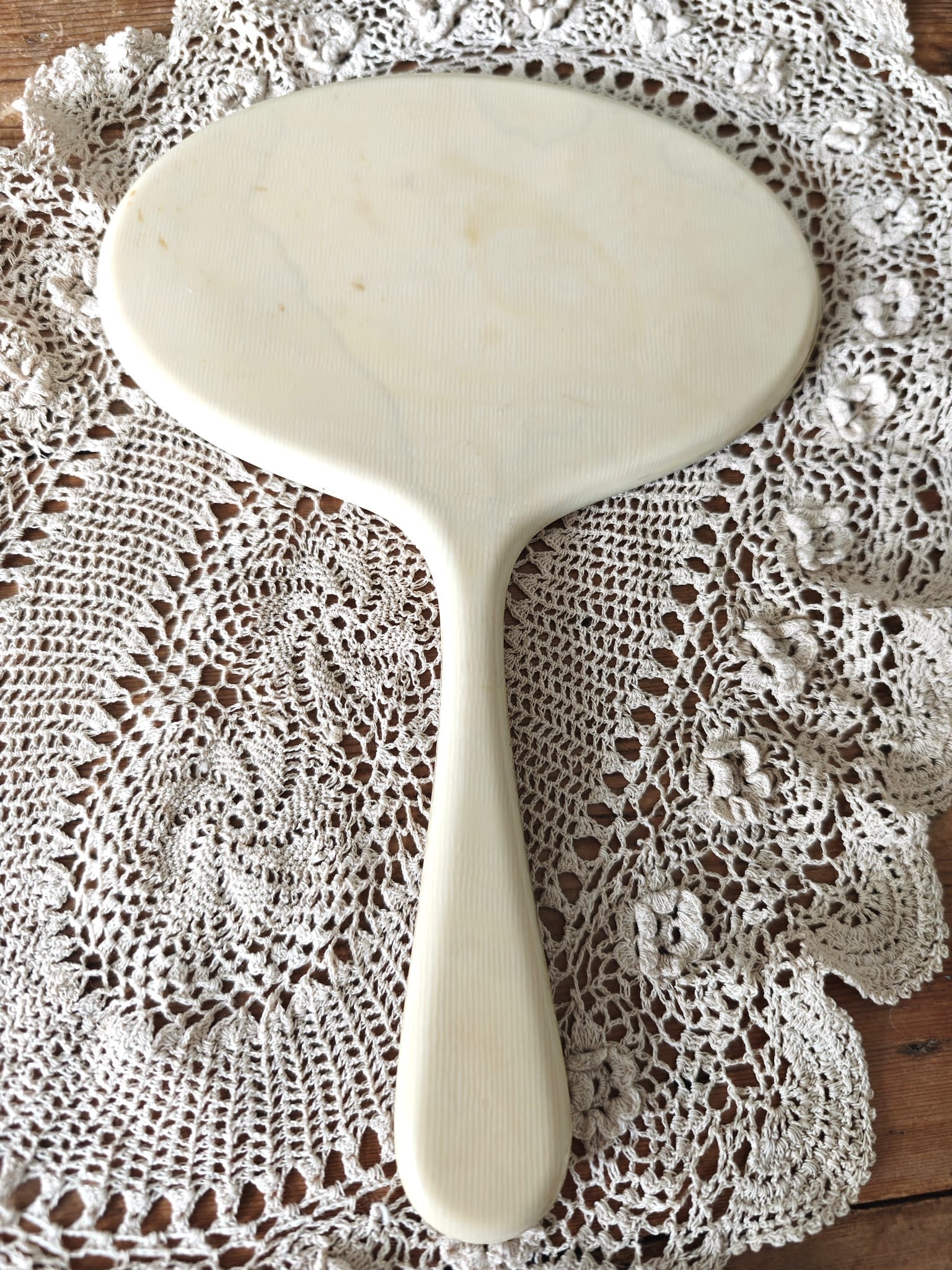 White hand mirror on a lace doily
