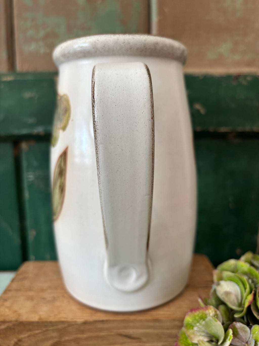 A white speckled ceramic pitcher with a vertical handle.