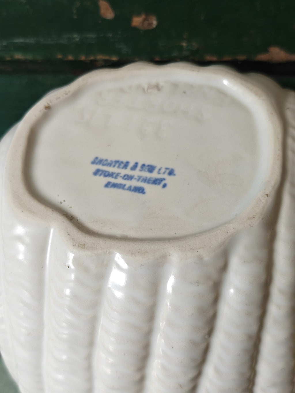 Close-up of the bottom of a white ribbed shell vase from Shorter and Son.