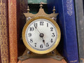 Small white clock face with brass case