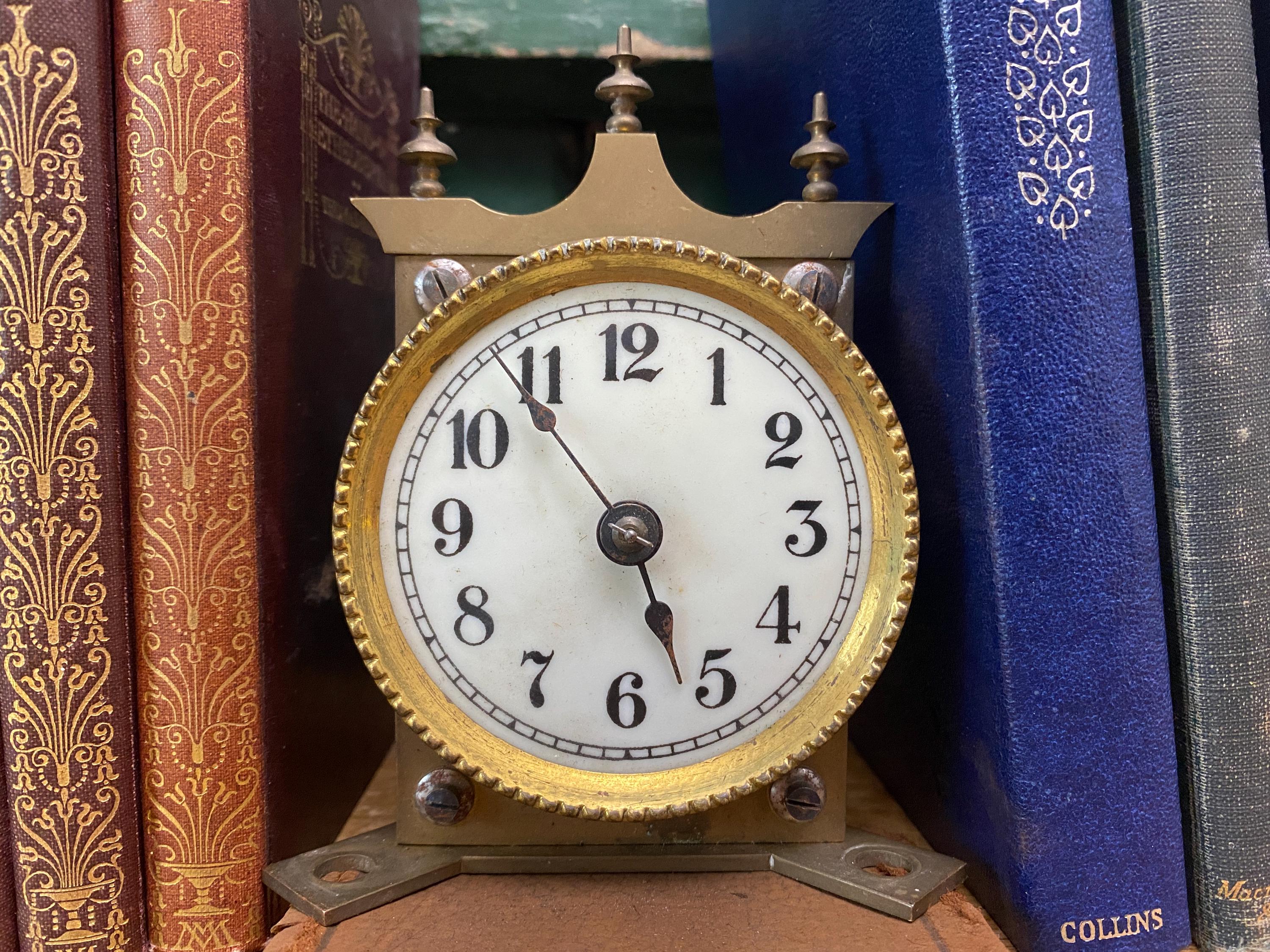Small white clock face with brass case