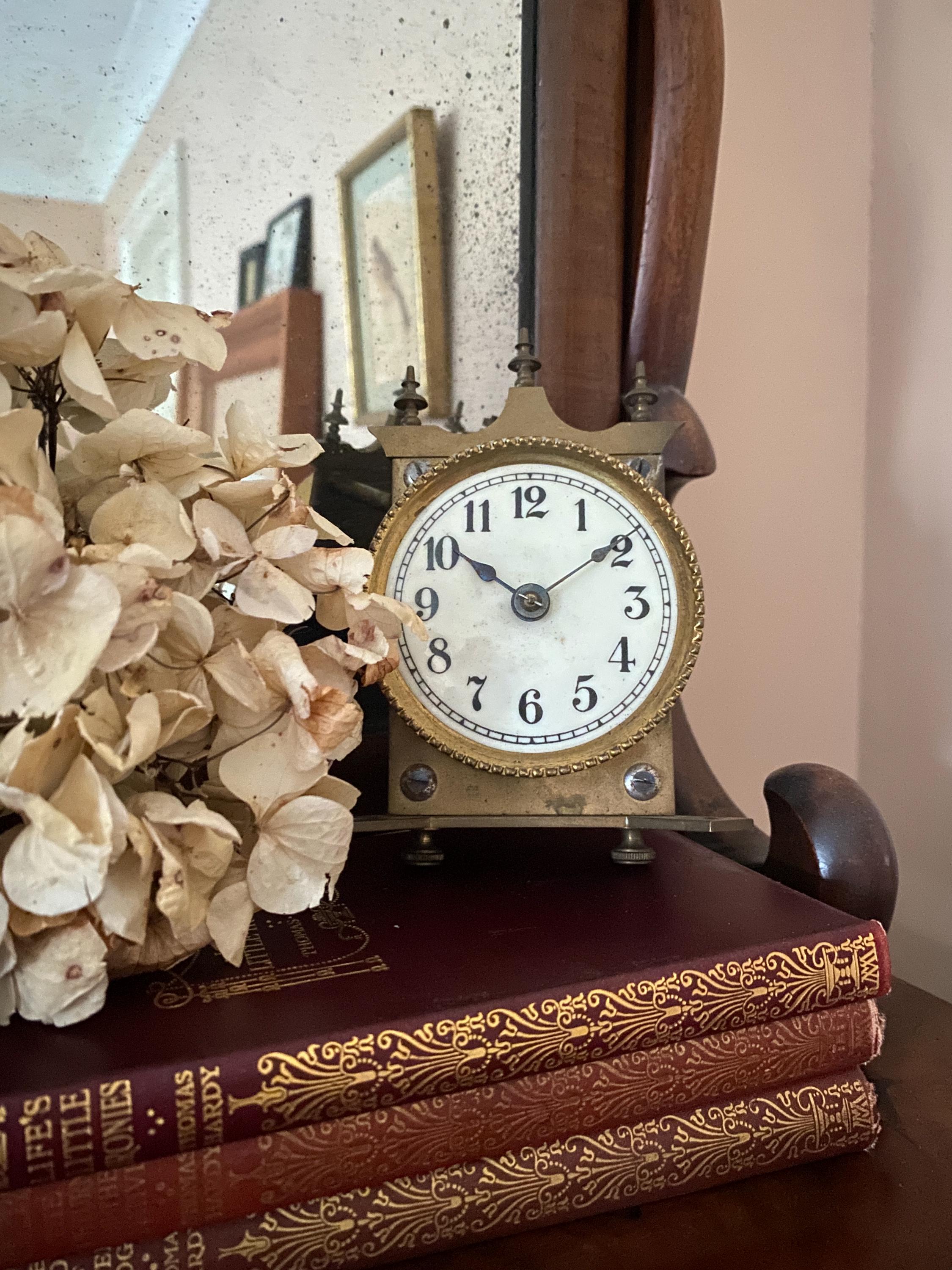 Decorative brass clock displayed with ornate books