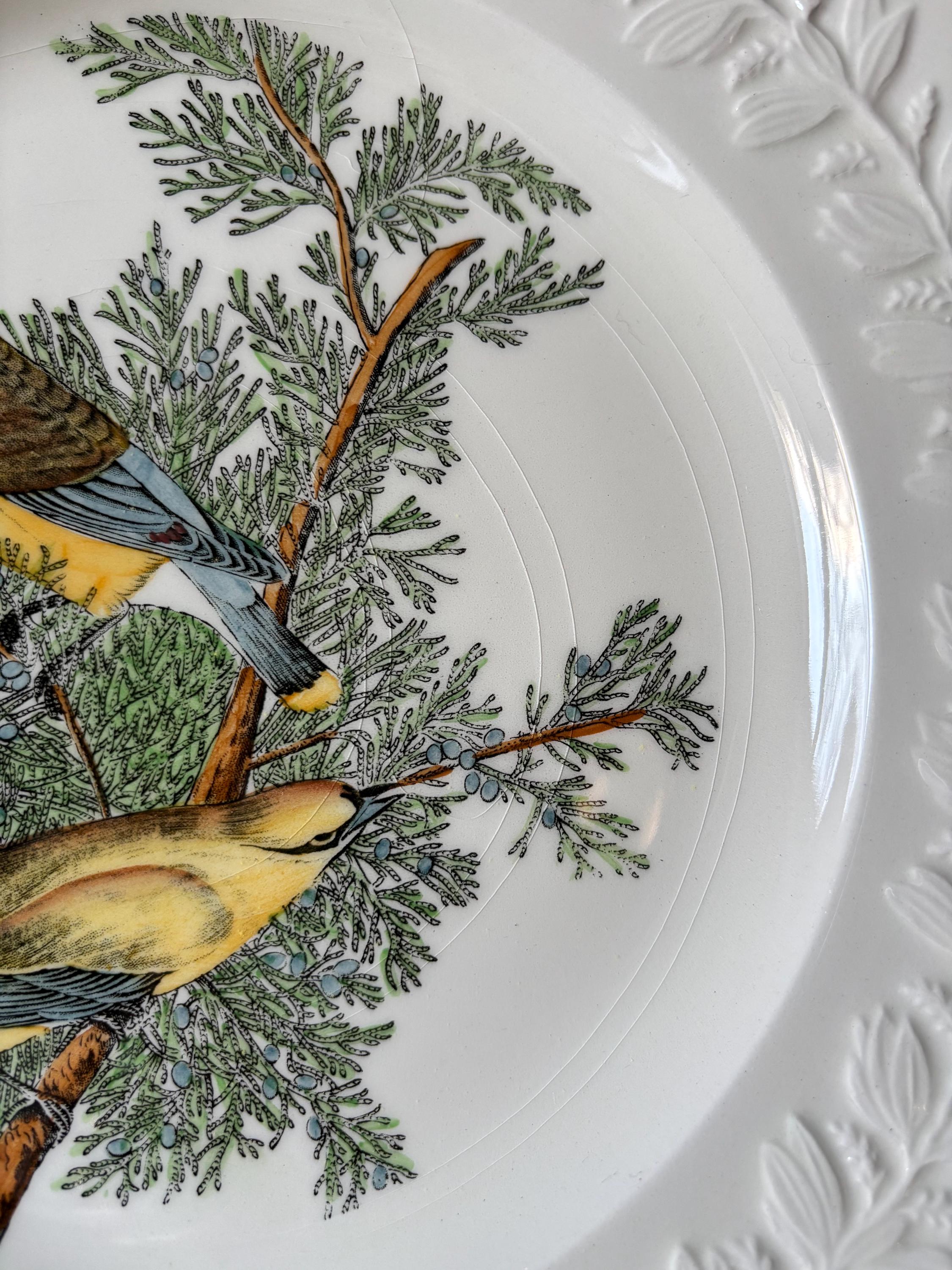 Close-up of decorative plate with bird and tree design and embossed leaf decoration