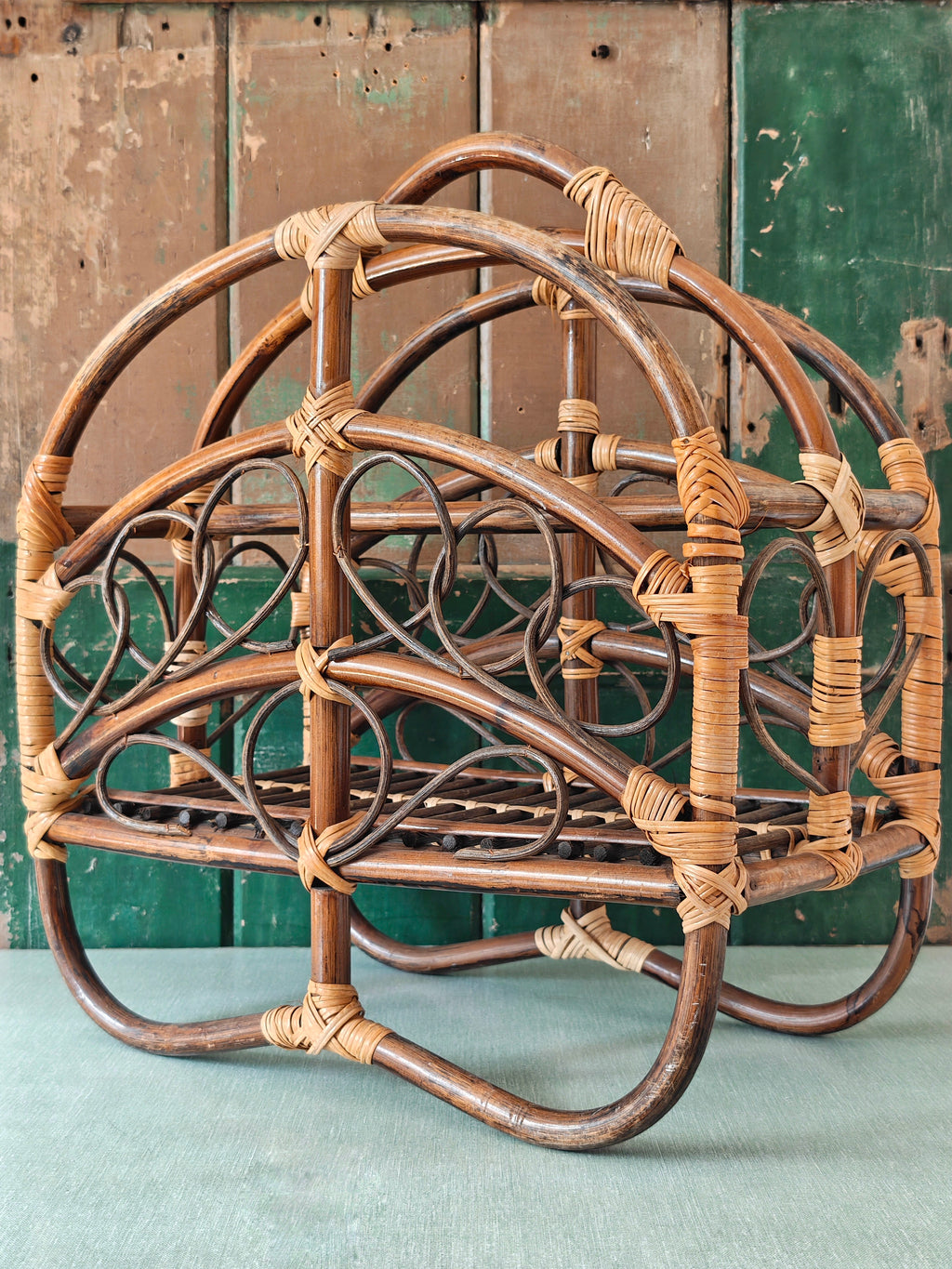 A vintage bamboo and rattan magazine rack with a rounded dome shape, featuring brown wooden frame and woven bamboo accents.