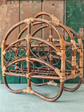 A vintage bamboo and rattan magazine rack with a rounded dome shape, featuring brown wooden frame and woven bamboo accents.