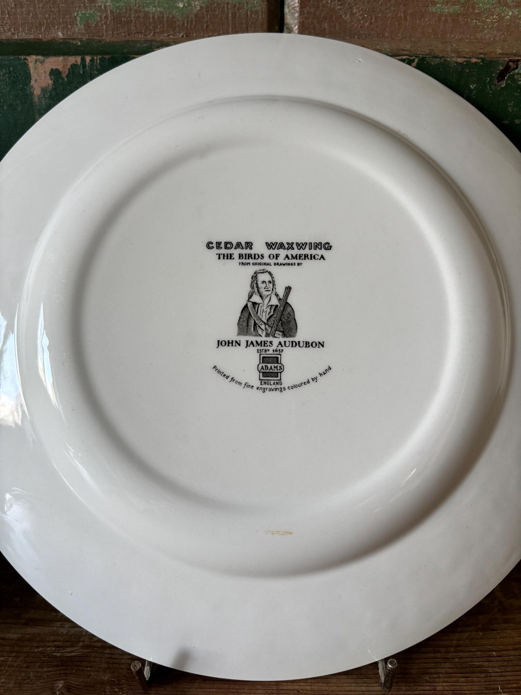 Back of a white plate with stamp showing makers mark and design description