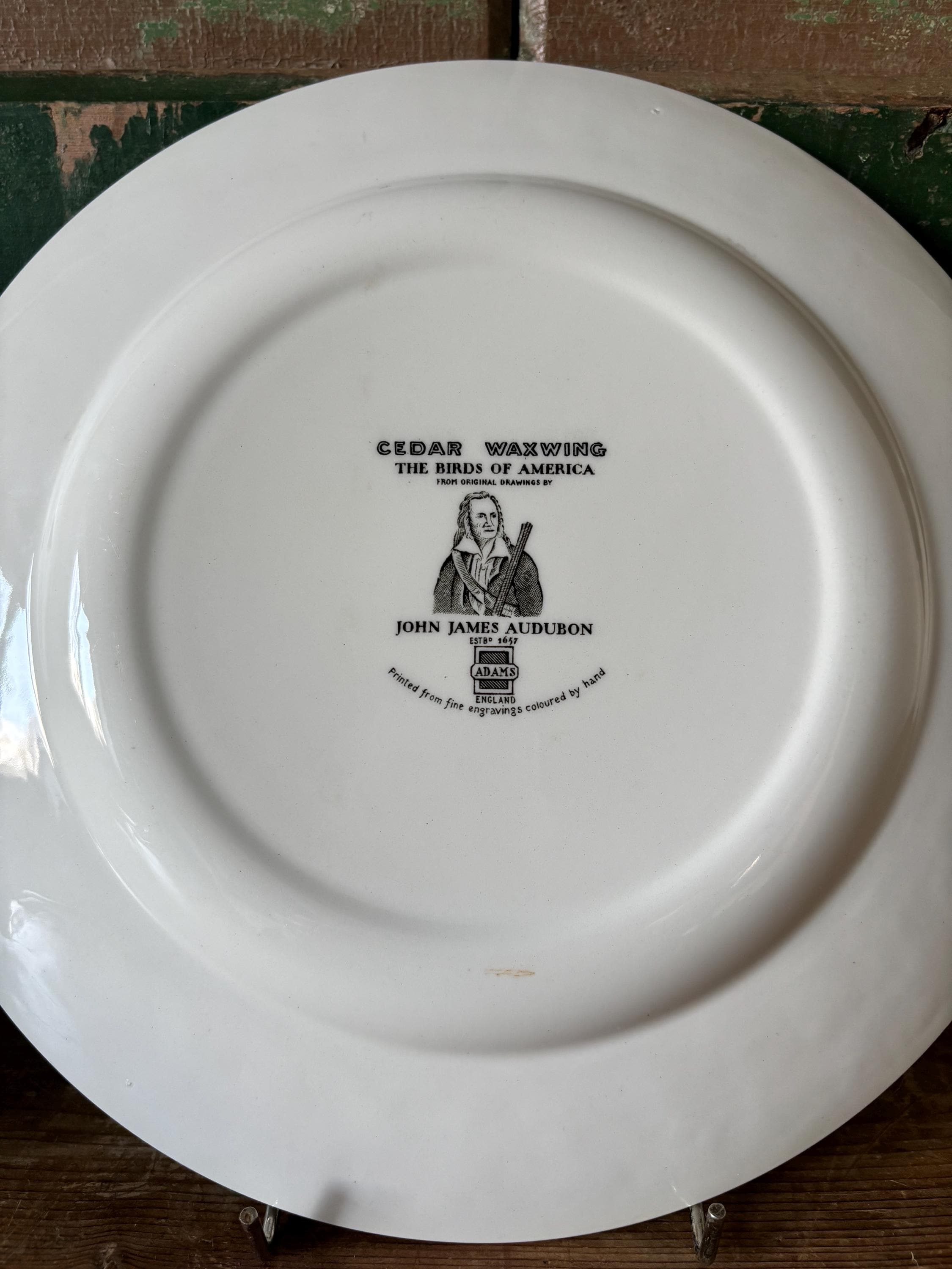 Back of a white plate with stamp showing makers mark and design description