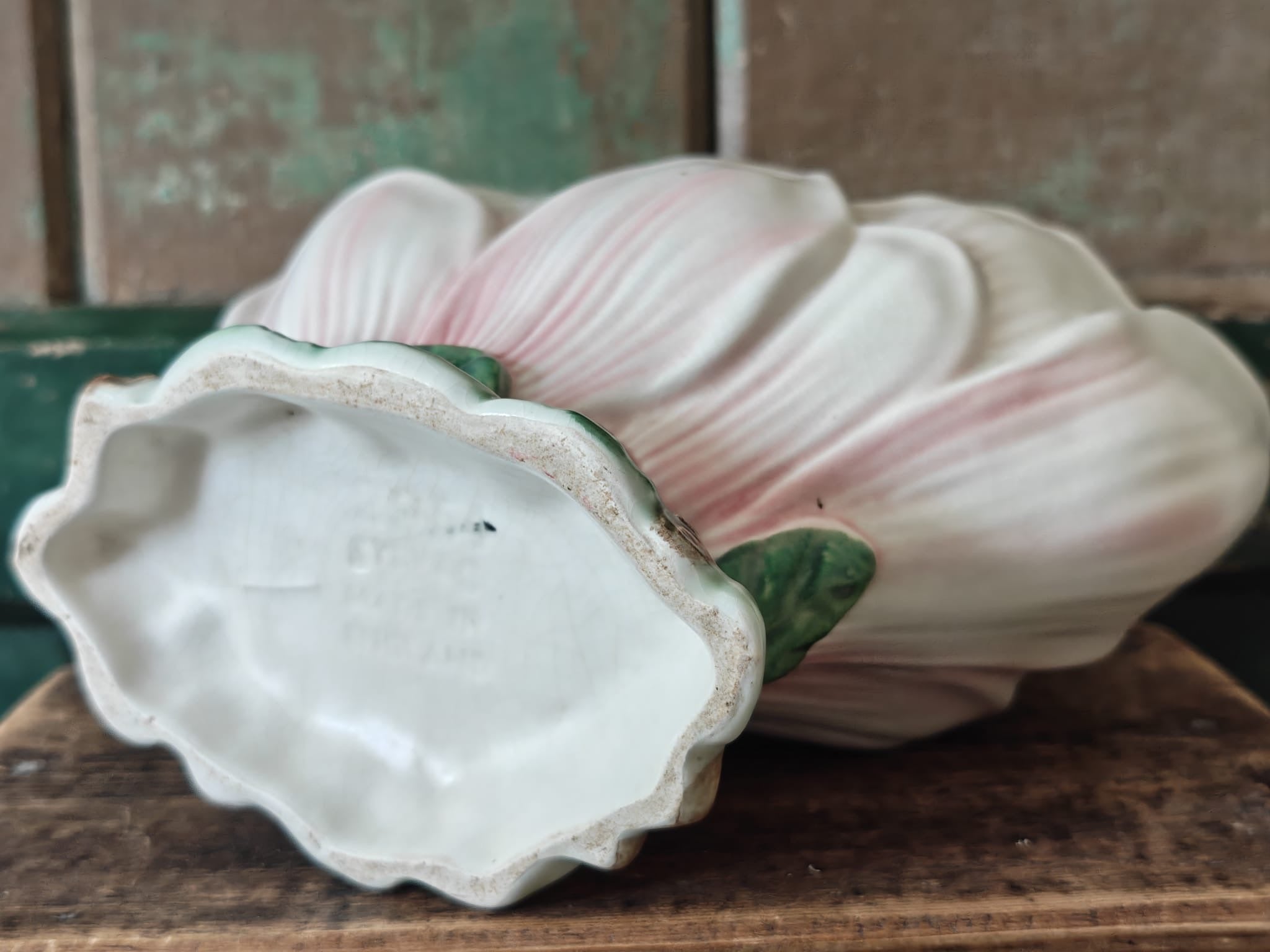 View of the underside of a vintage-style ceramic flower vase formed as a pink and green magnolia flower, showing the makers mark