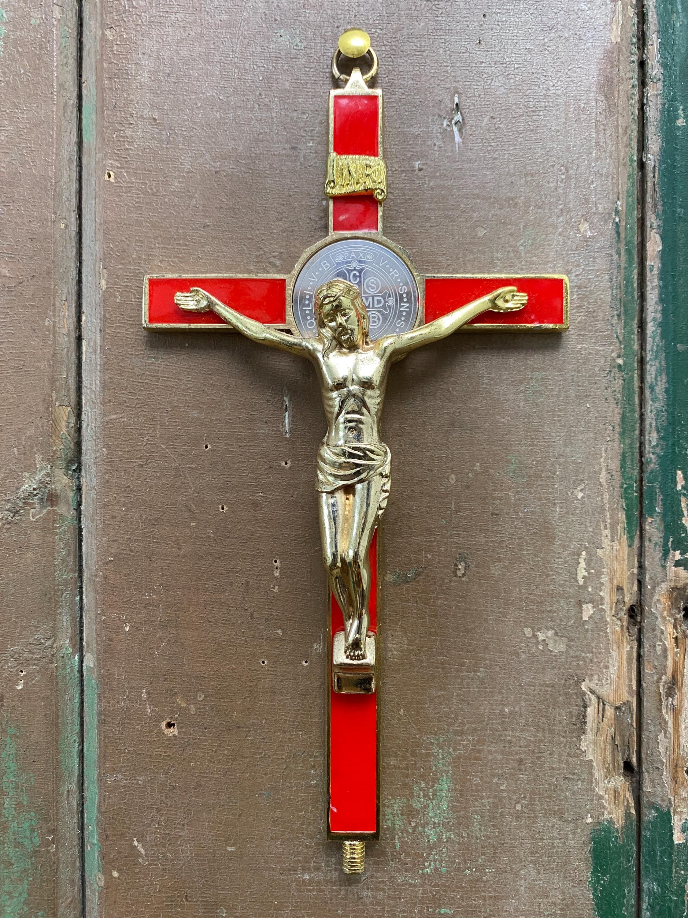 Decorative crucifix with red and gold accents displayed hanging on a wall.
