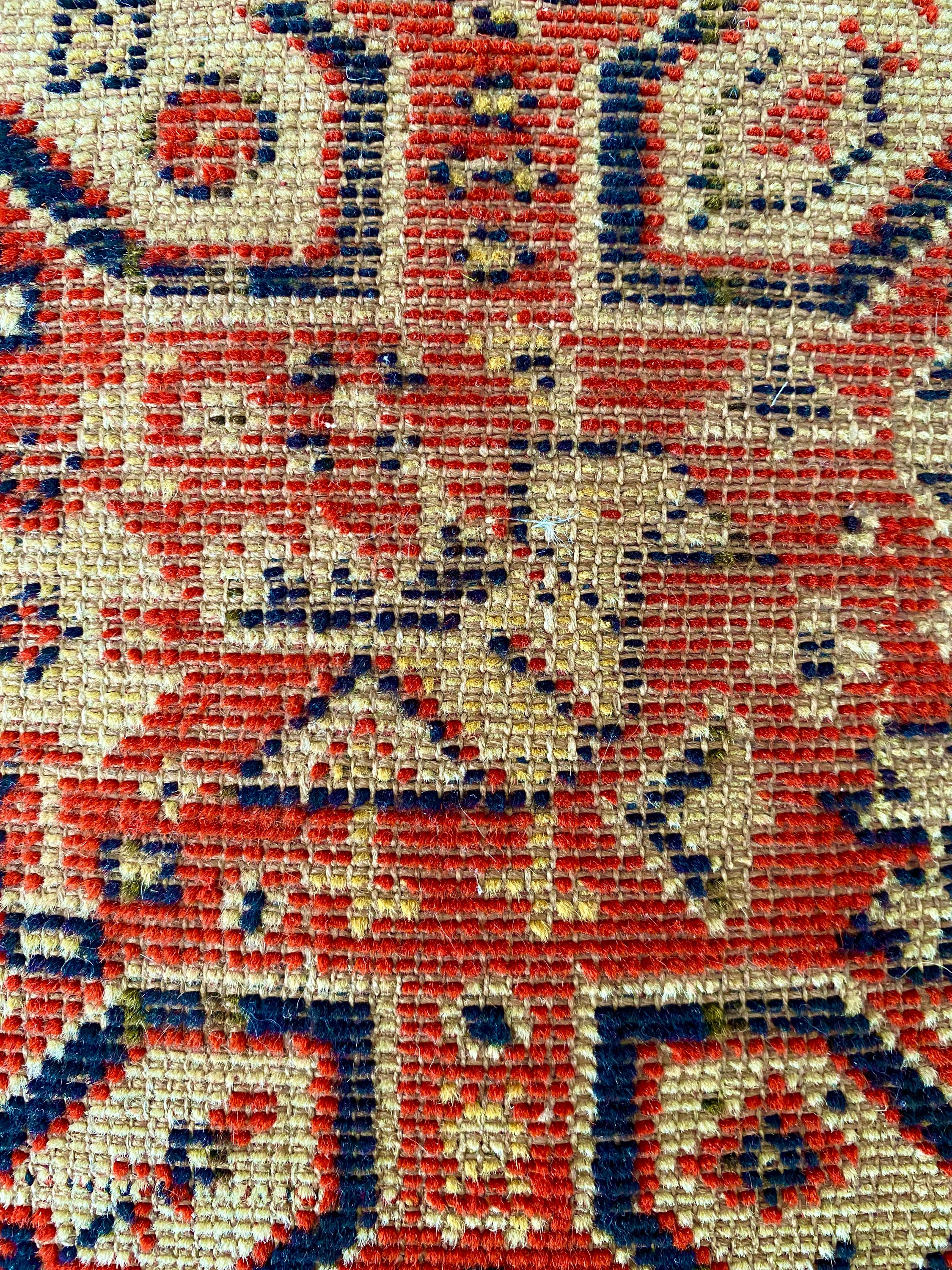 Close-up of a woven patterned fabric with red, blue, and beige colors.