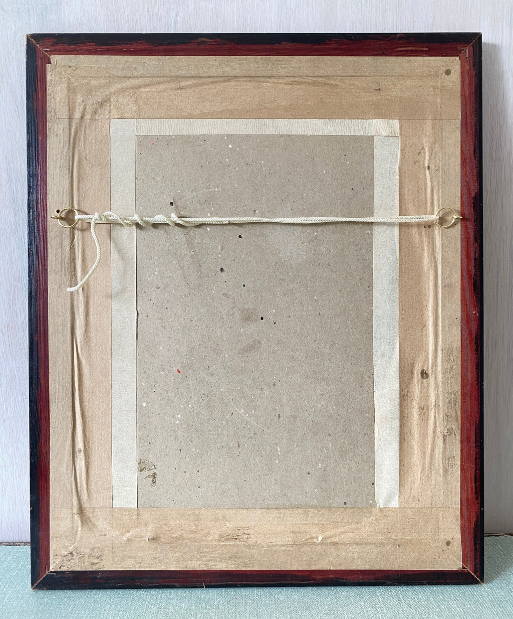 Backside of a framed artwork with string and cardboard