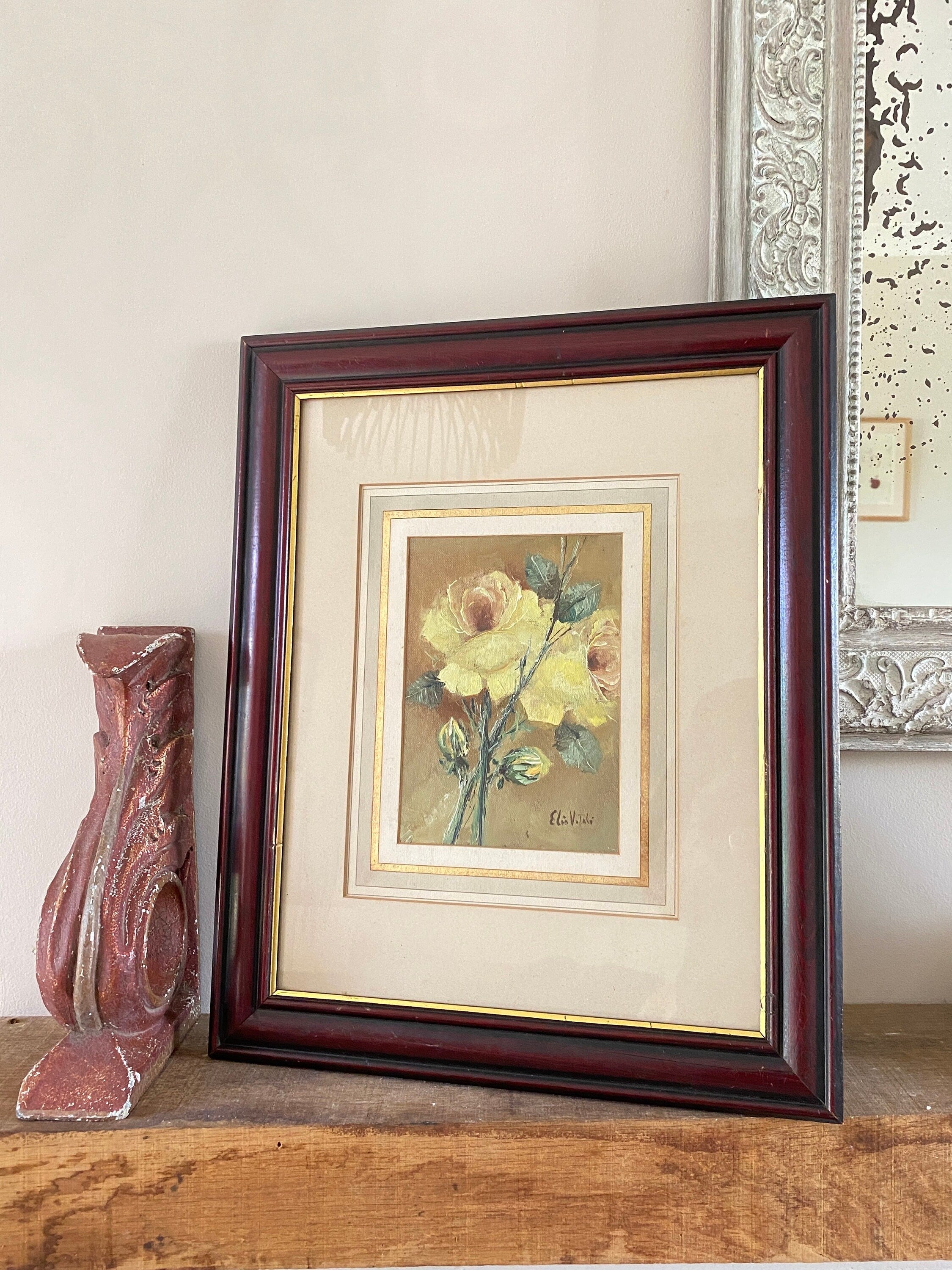 Framed painting of yellow flowers propped on a shelf