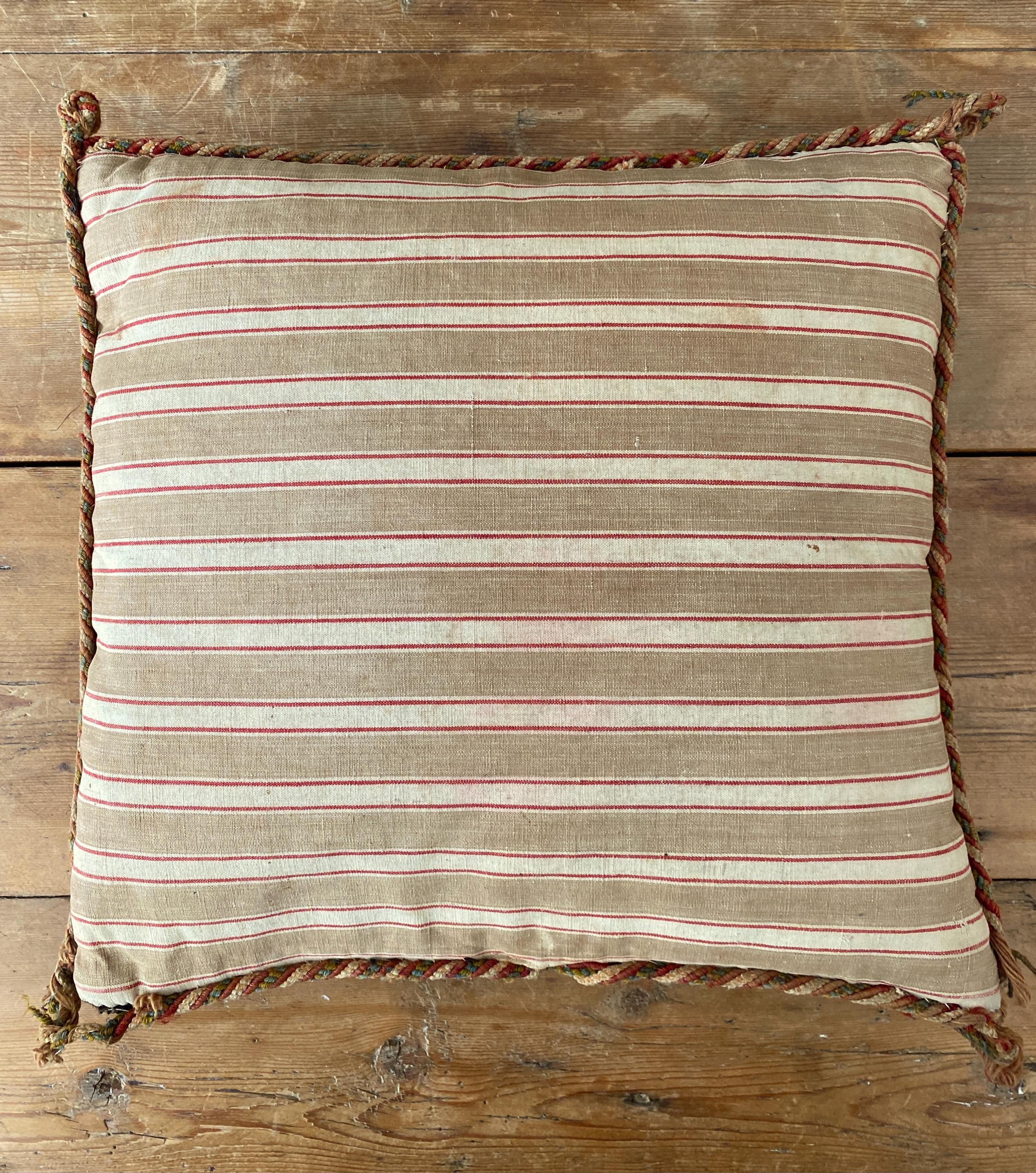 Striped pillow with red lines and braded trim