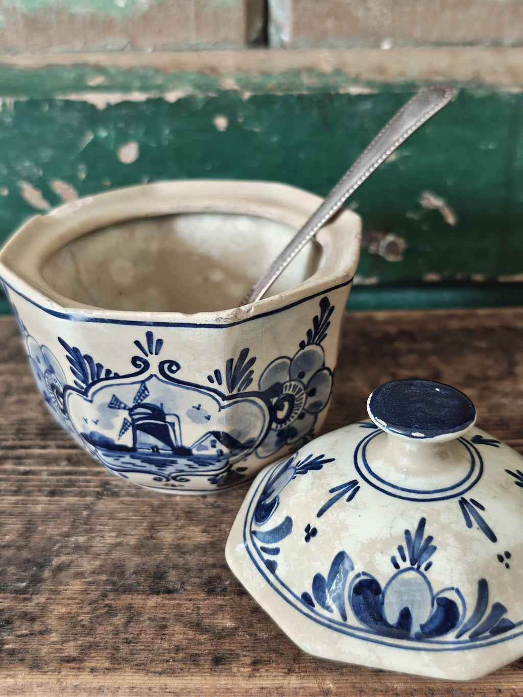 A vintage blue and white ceramic sugar bowl with its matching lid placed in front.