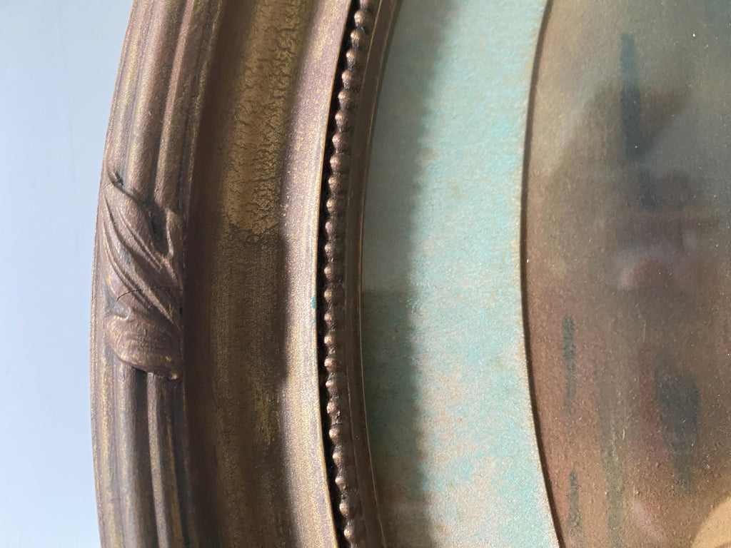 Close-up of part of an oval gold frame and picture mount