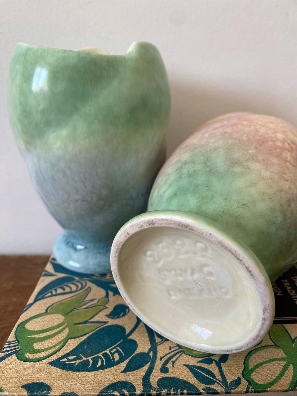 A close up of two ceramic vases one showing the base with the makers mark
