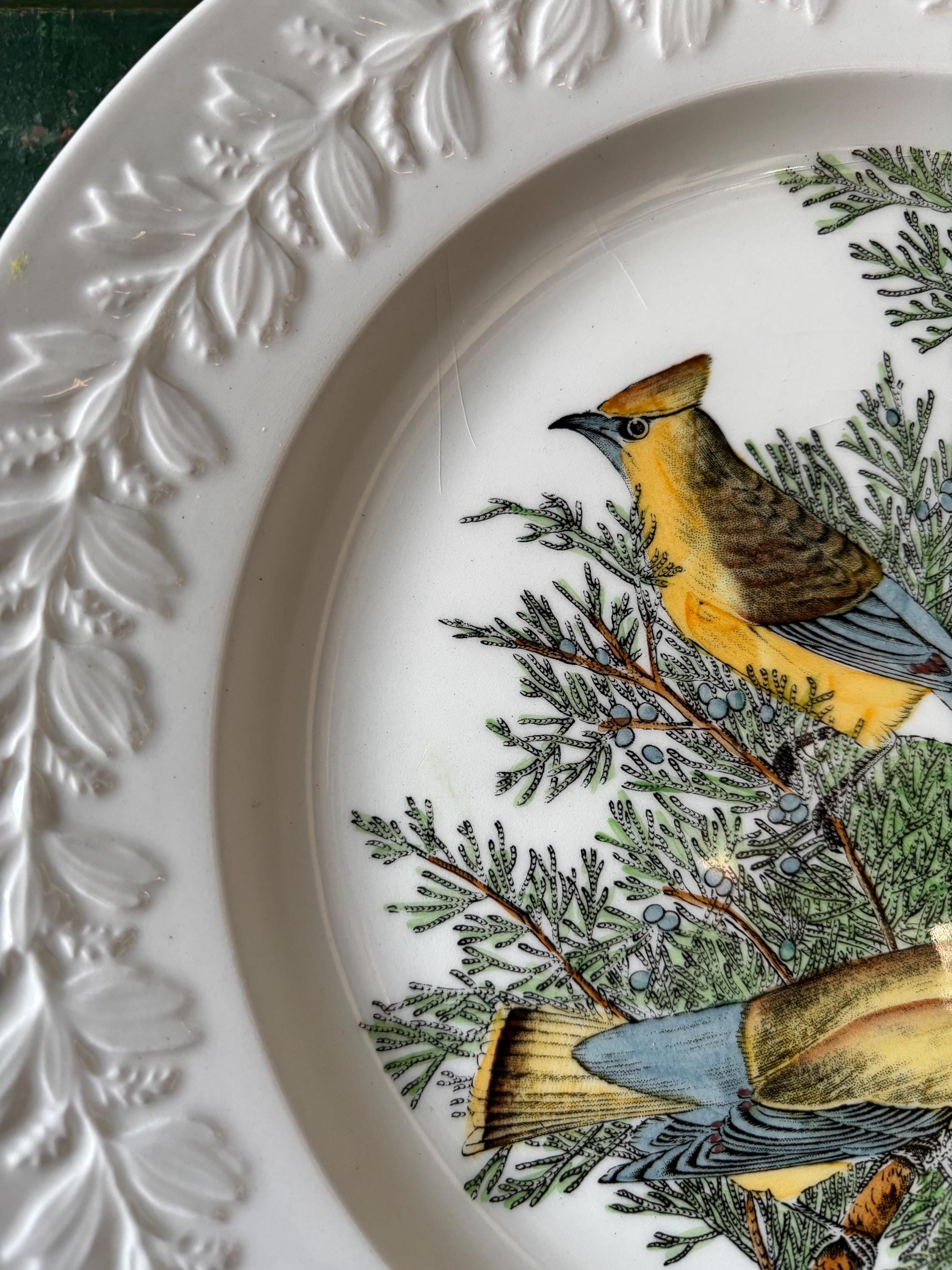 Close-up of decorative plate with bird and tree design and embossed leaf decoration