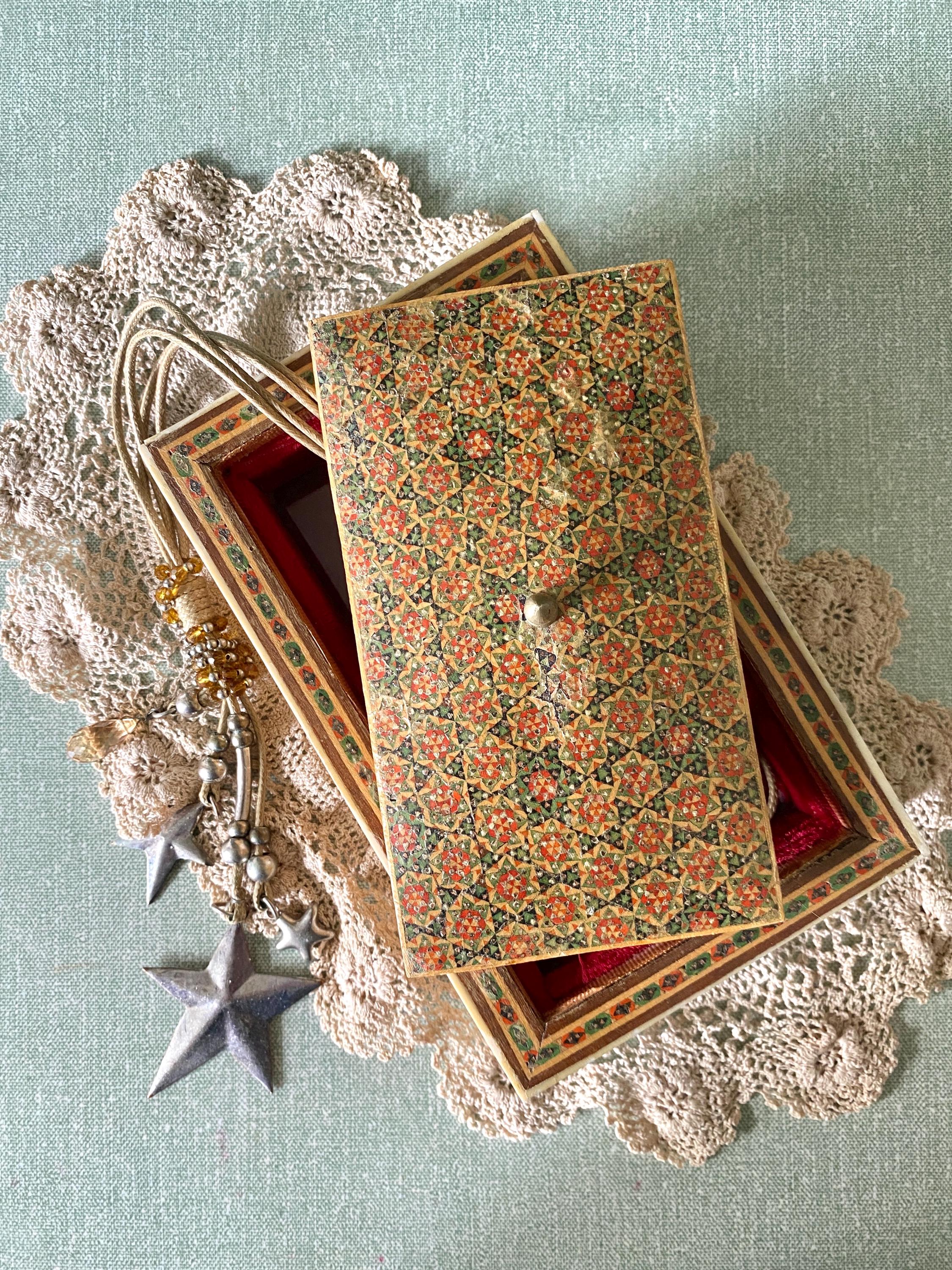 Partially open decorative box with intricate red and green geometric patterns