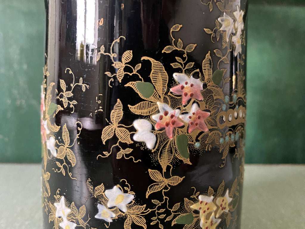 close up of intricate gold floral decoration on a black glazed jug