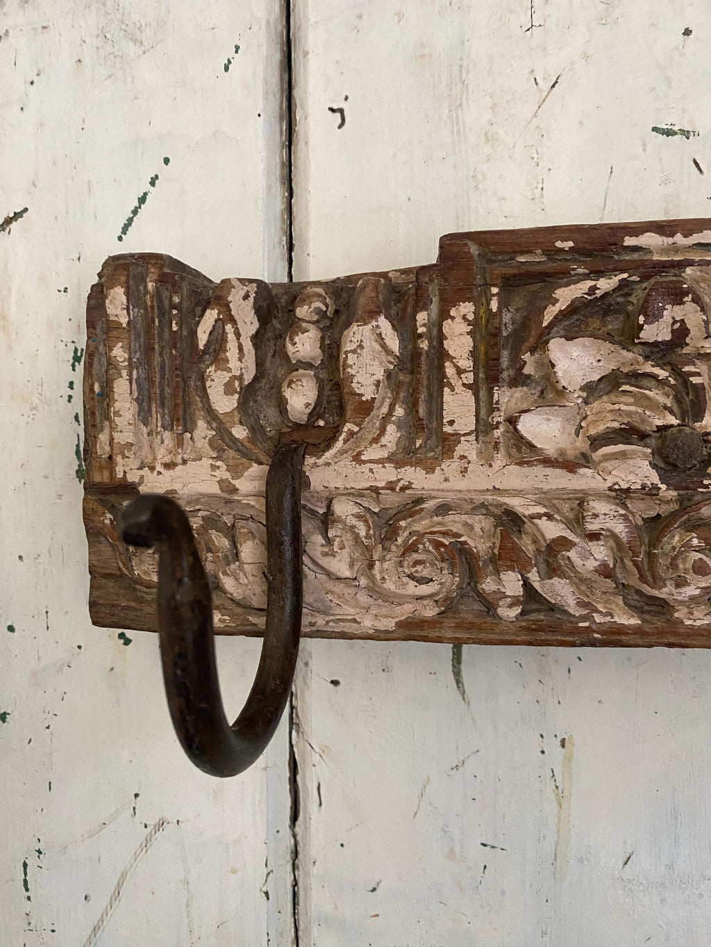 Metal hook on a wooden block with intricate carvings 