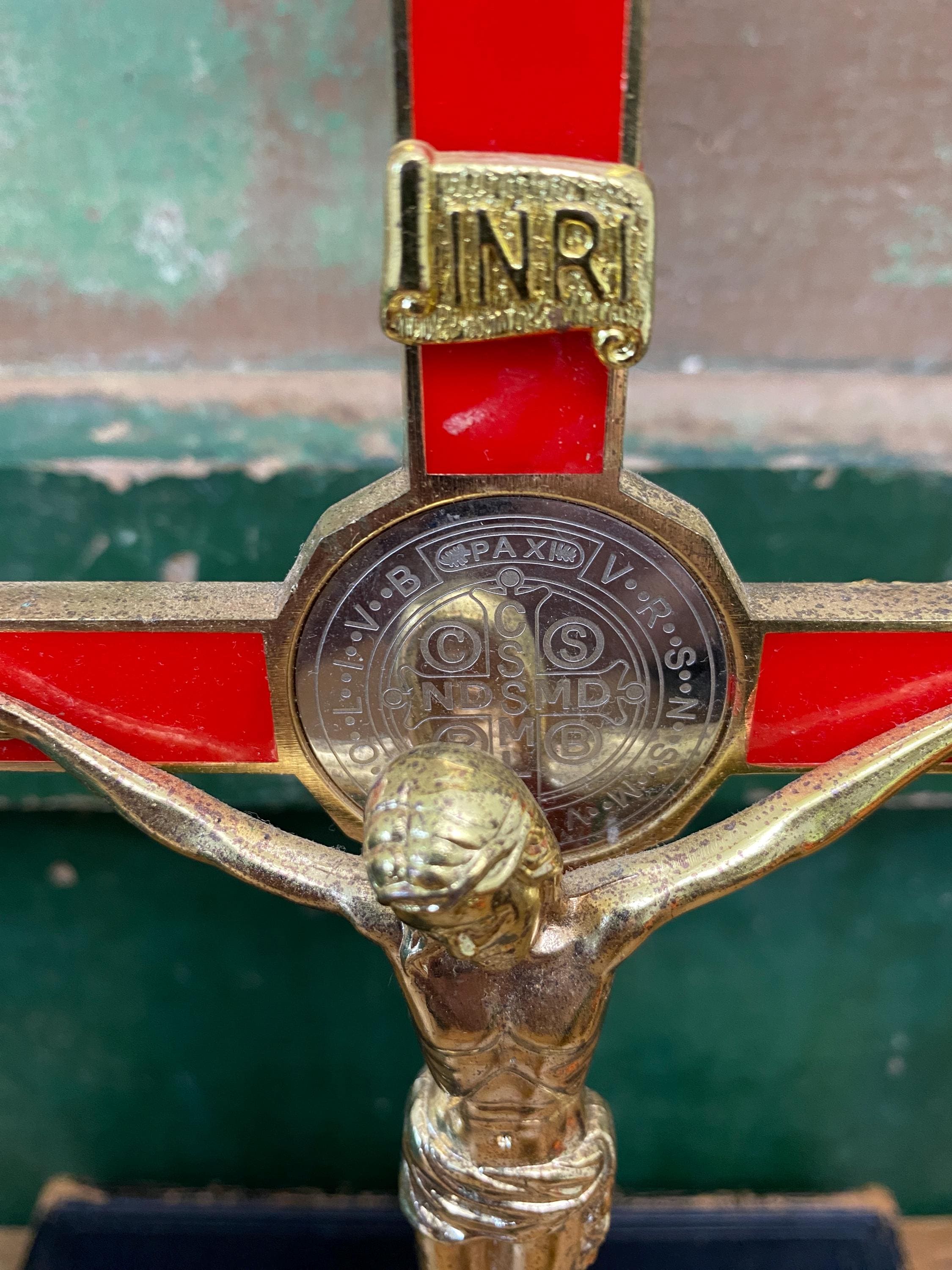Close-up of a gold and red crucifix with 'INRI' inscription and inset silver medallion.