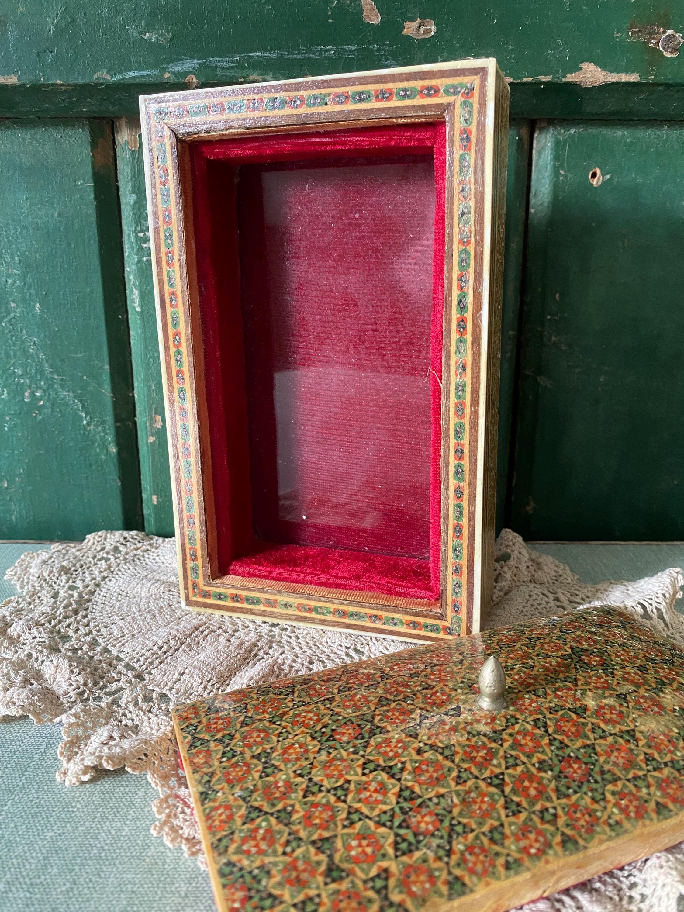 Decorative box with a red interior and ornate decoration with lid in foreground