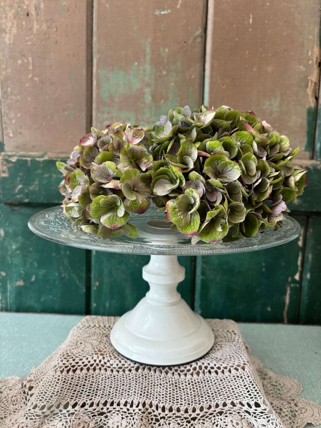 A pressed glass cake stand with a cream pedestal base.