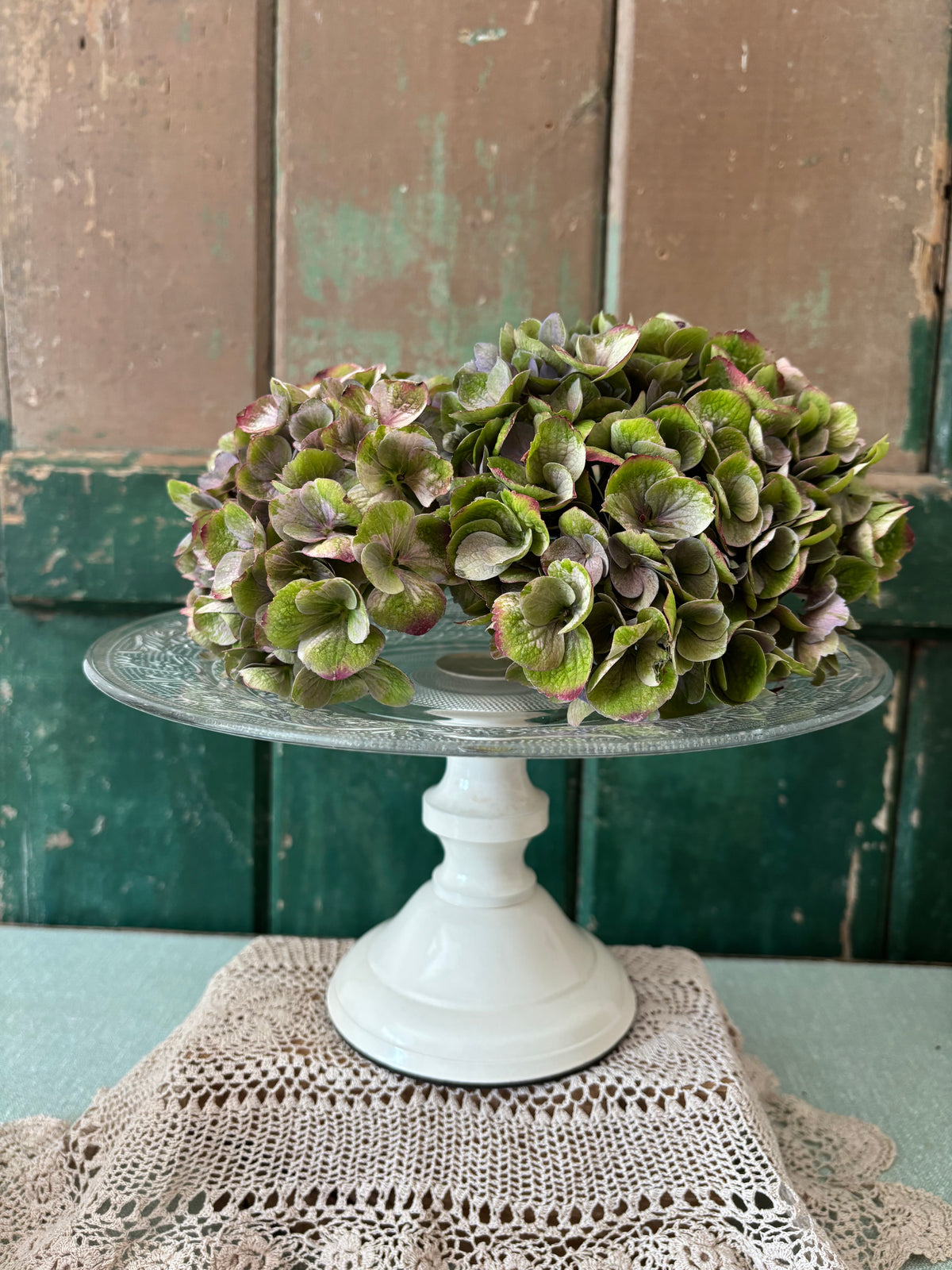 A pressed glass cake stand with a cream pedestal base.