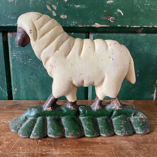 Decorative cast iron sheep figurine on a green base