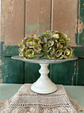  A cream pedestal cake stand with a clear glass top.
