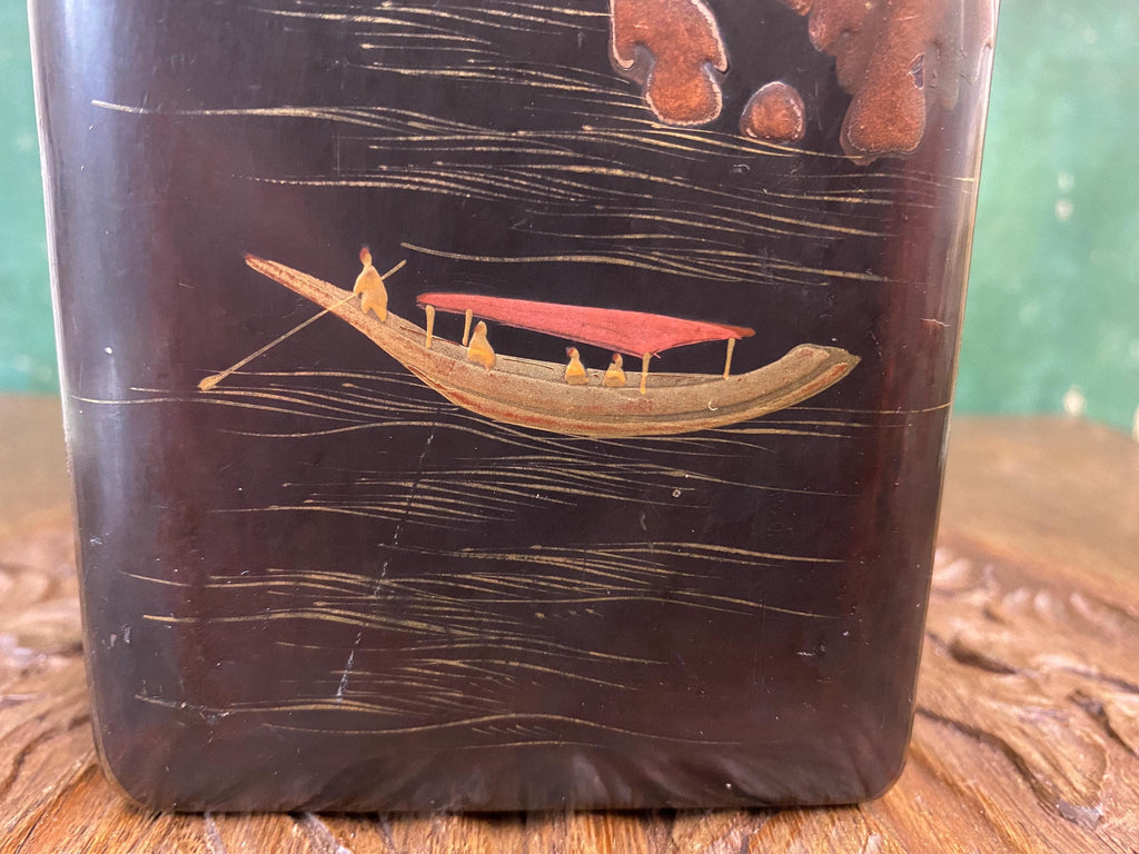 Decorative item with a boat and people design on a dark background