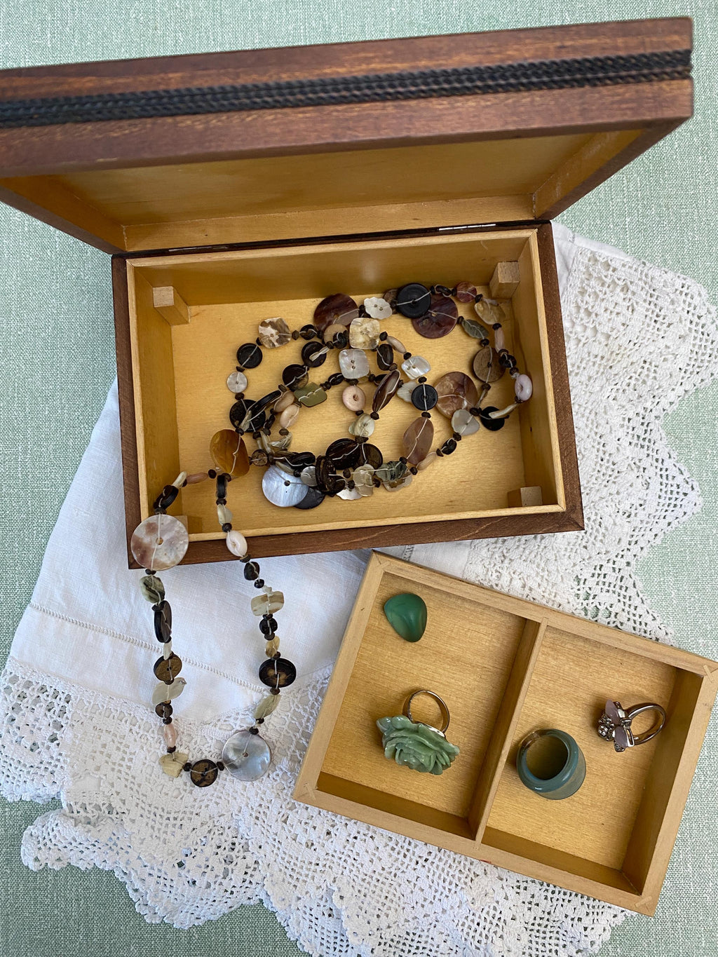 Wooden jewelry box open to show necklaces and rings 