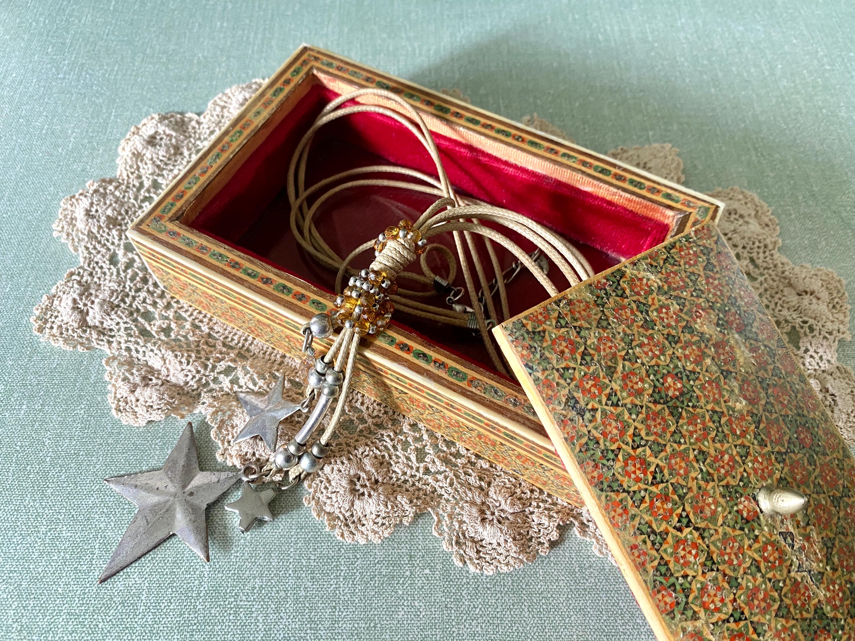 Decorative box with intricate red and green geometric patterns open to show red interior