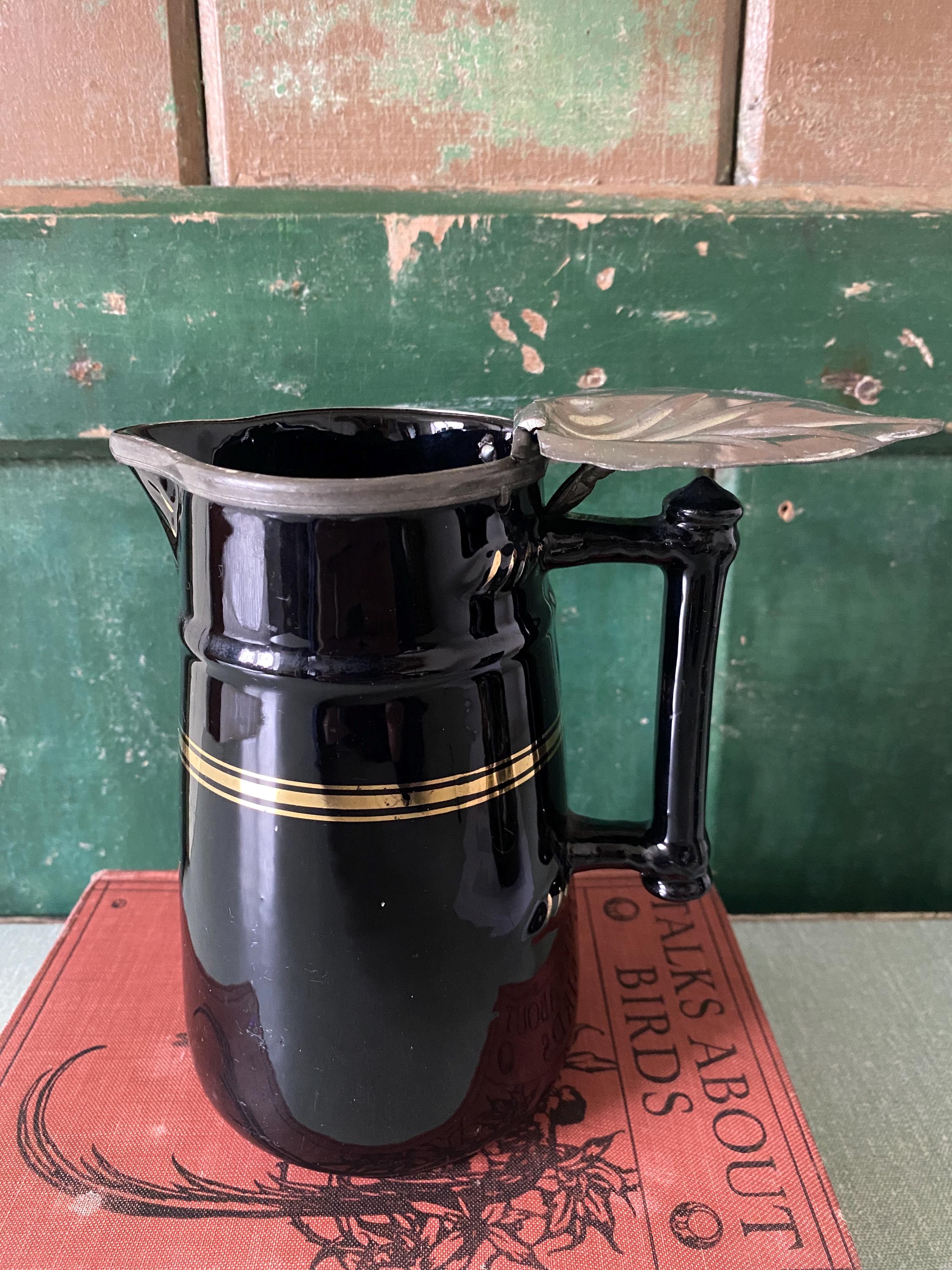 Black ceramic pitcher with gold stripe and hinged metal lid