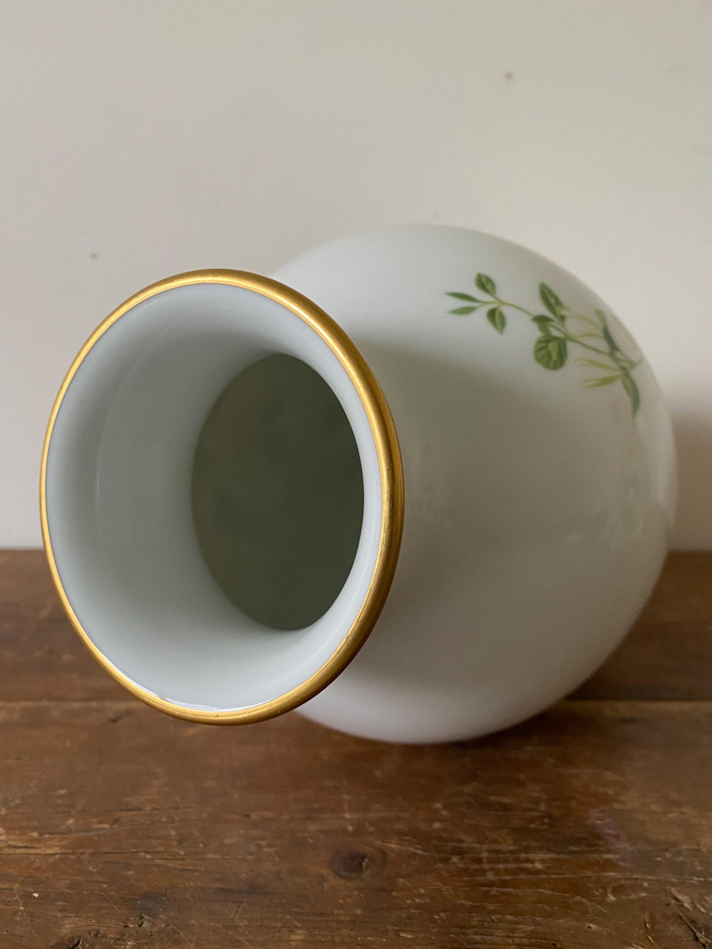 White ceramic vase with gold rim and green leaf design