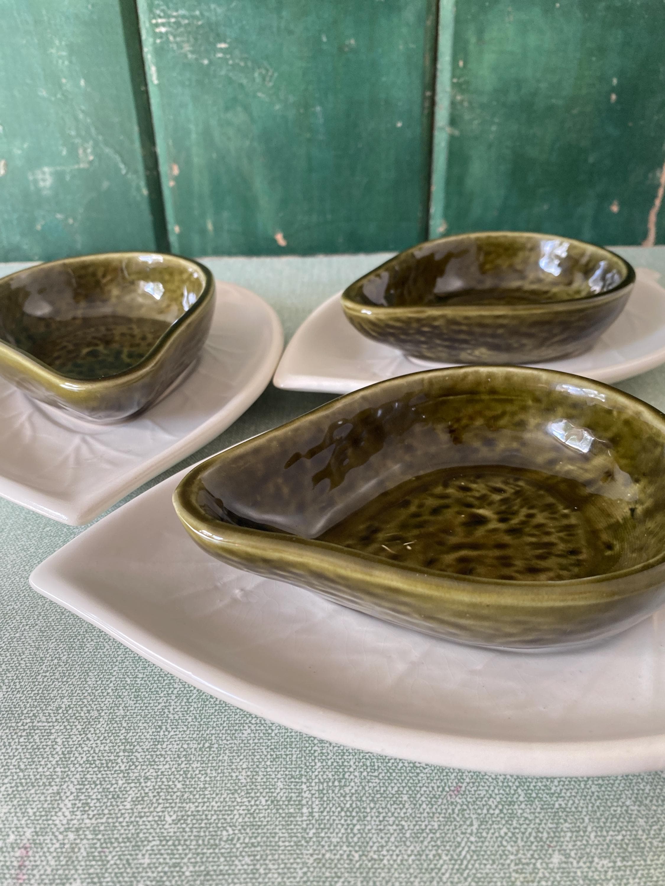 Three green avocado shaped dishes with white saucers