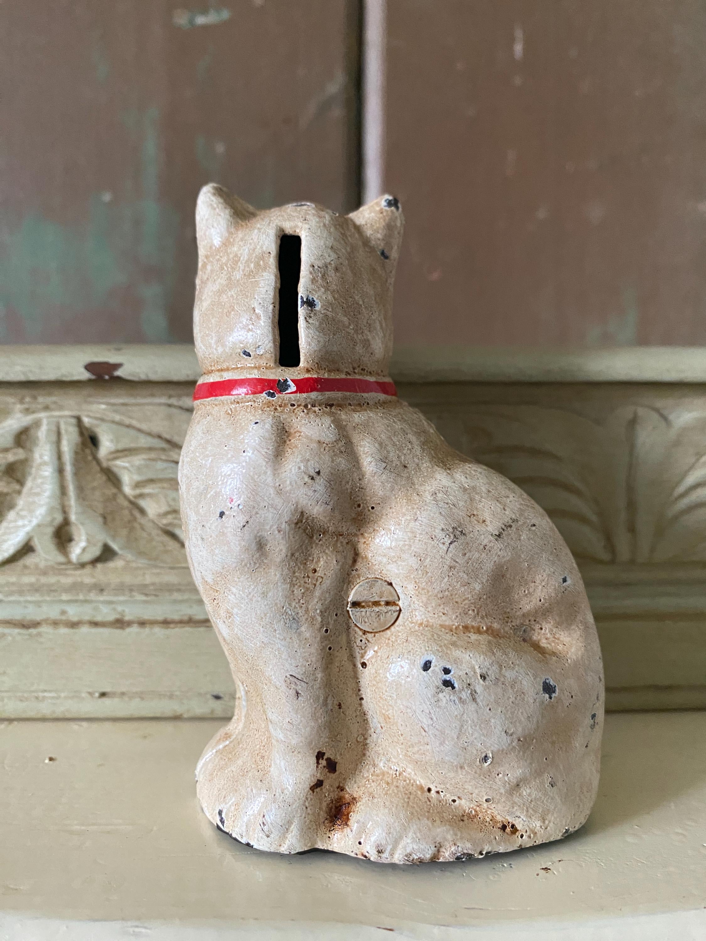 Vintage metal cat-shaped money box with a red ribbon 