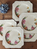 A set of five vintage cream ceramic plates with embossed floral borders and painted pink flowers.