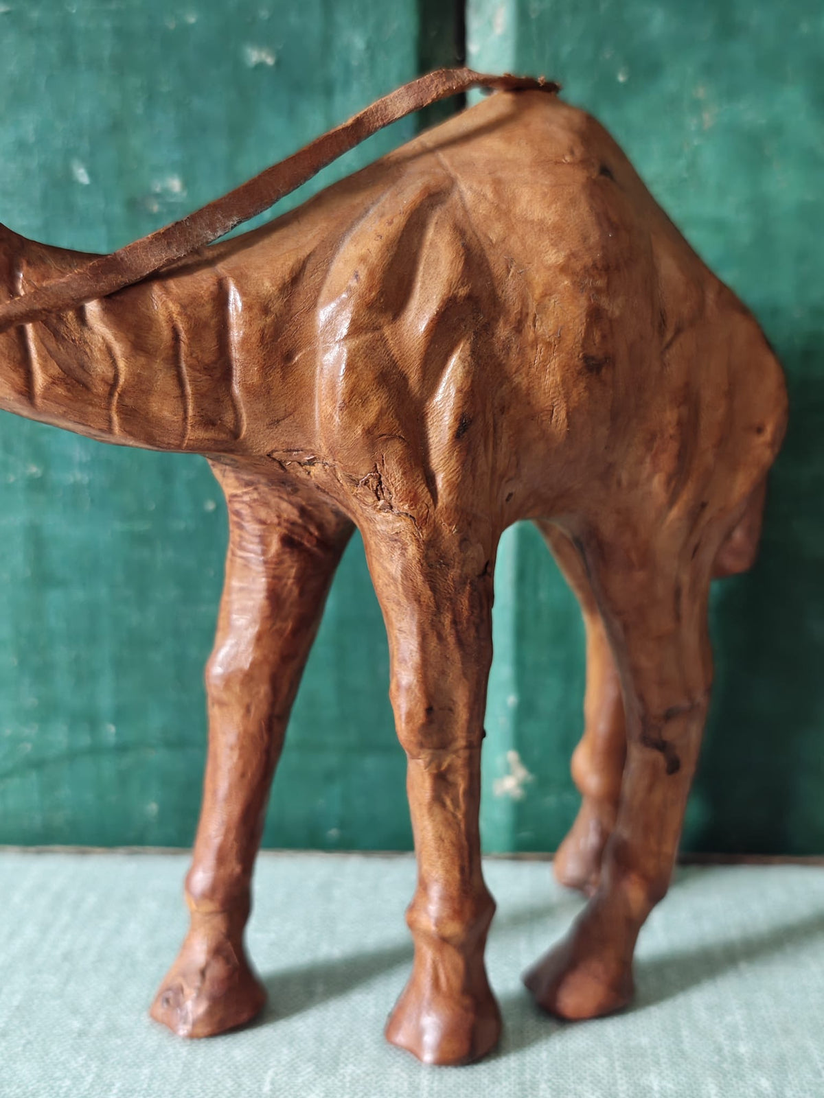 Close-up of the side and legs of a brown leather covered camel figurine