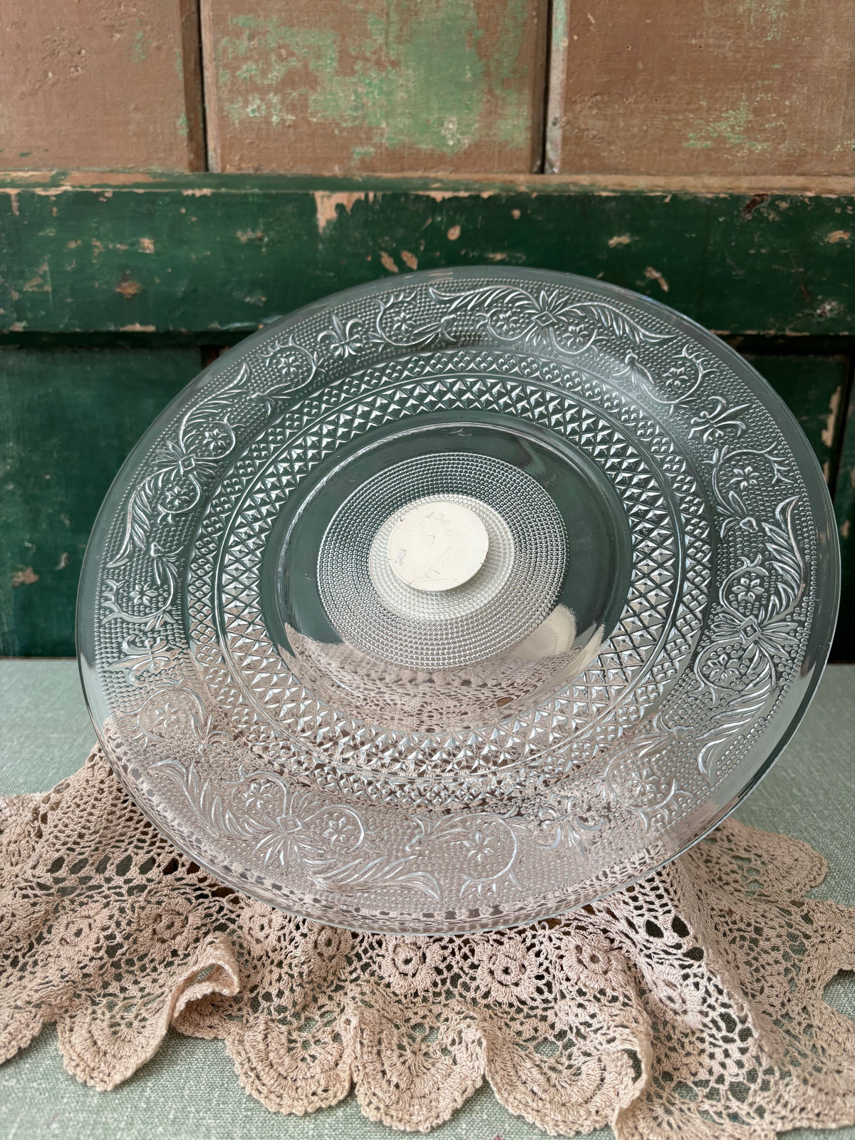 A clear cut-glass serving platter with ornate floral and geometric patterns.