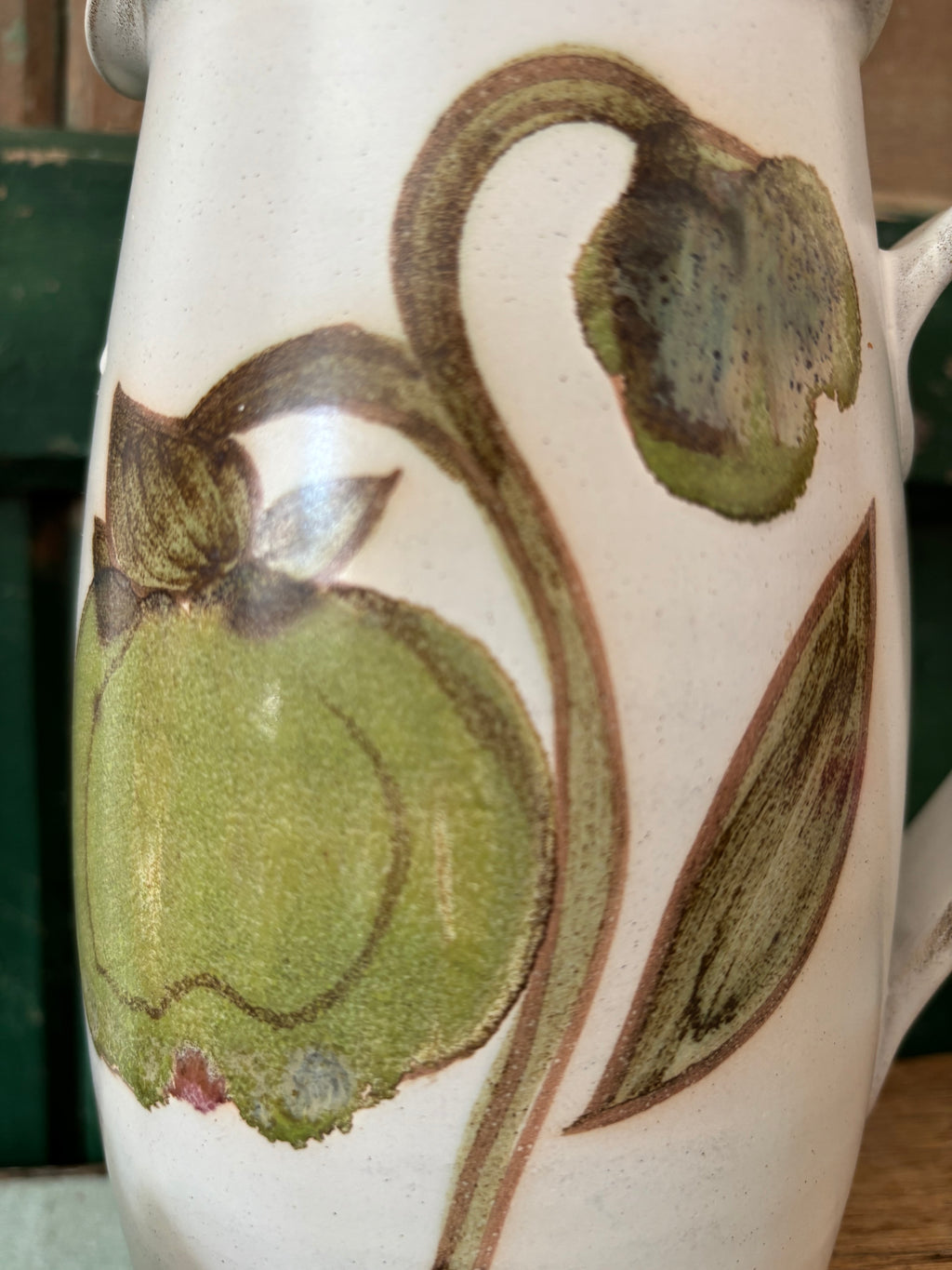 Close-up of a ceramic pitcher featuring a hand-painted magnolia bud.