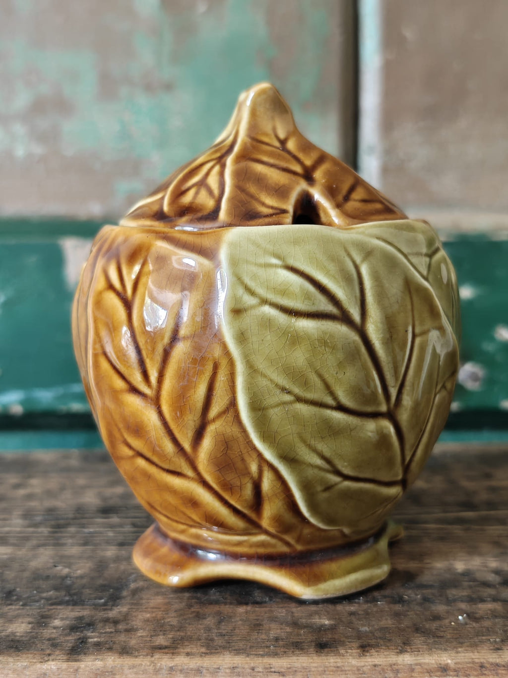 A ceramic lidded container with a leaf-like embossed pattern in a warm olive-gold glaze.