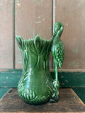 A dark green ceramic vase shaped like a lotus flower with a sculpted heron figure rising from the right side.