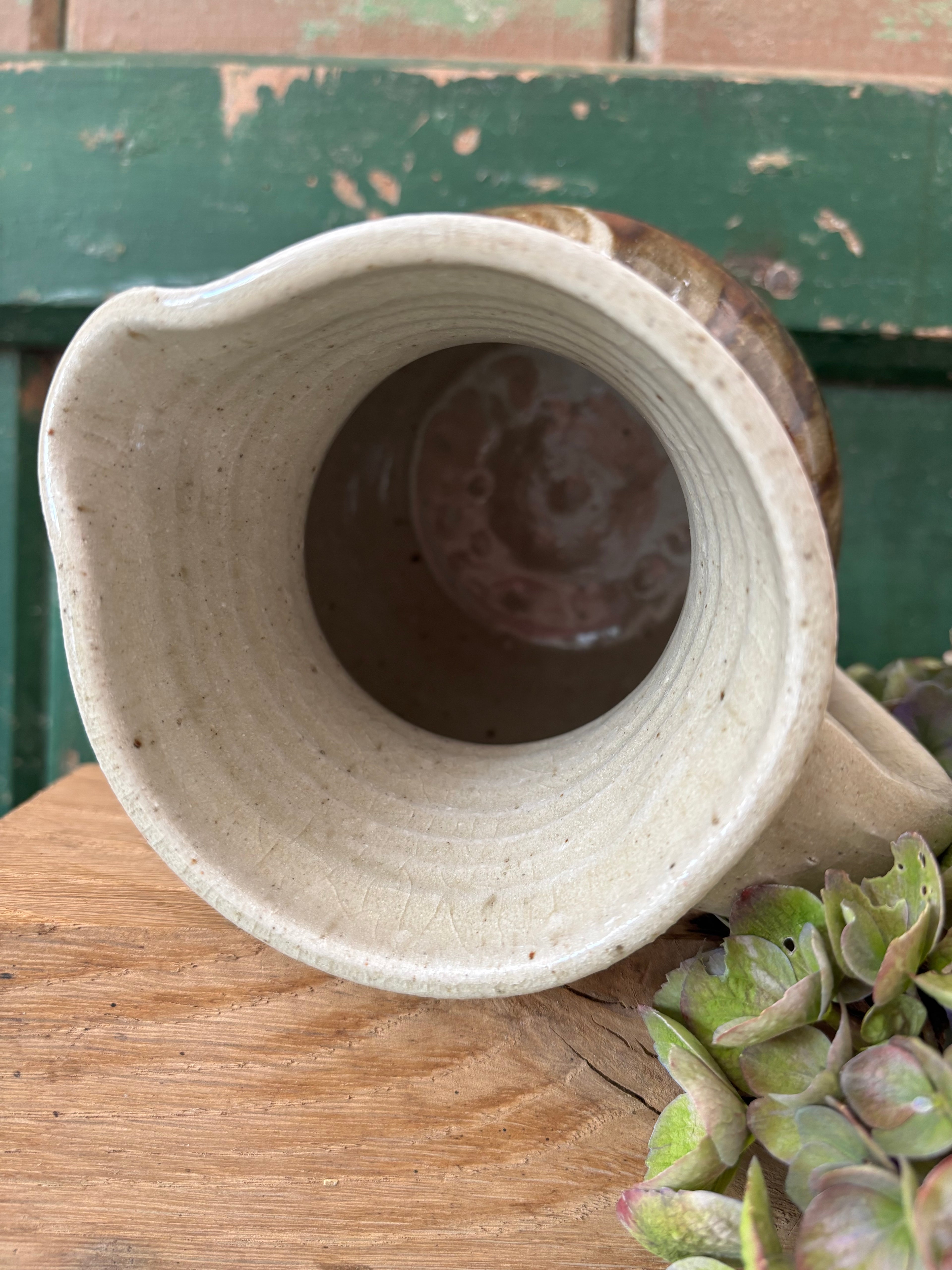 A handmade ceramic pitcher showing the interior.