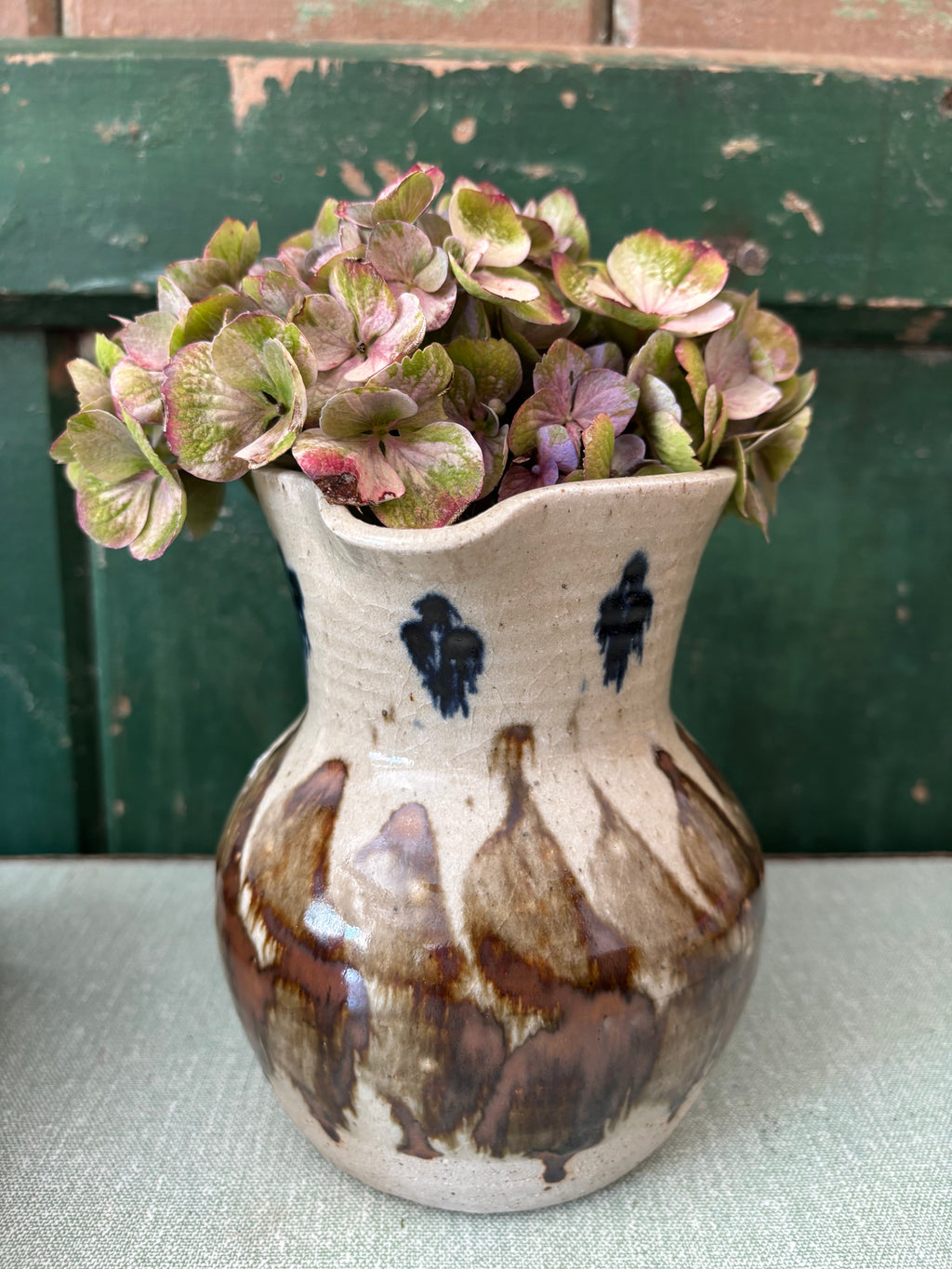 A handmade ceramic vase with an abstract brown and beige marbled glaze.