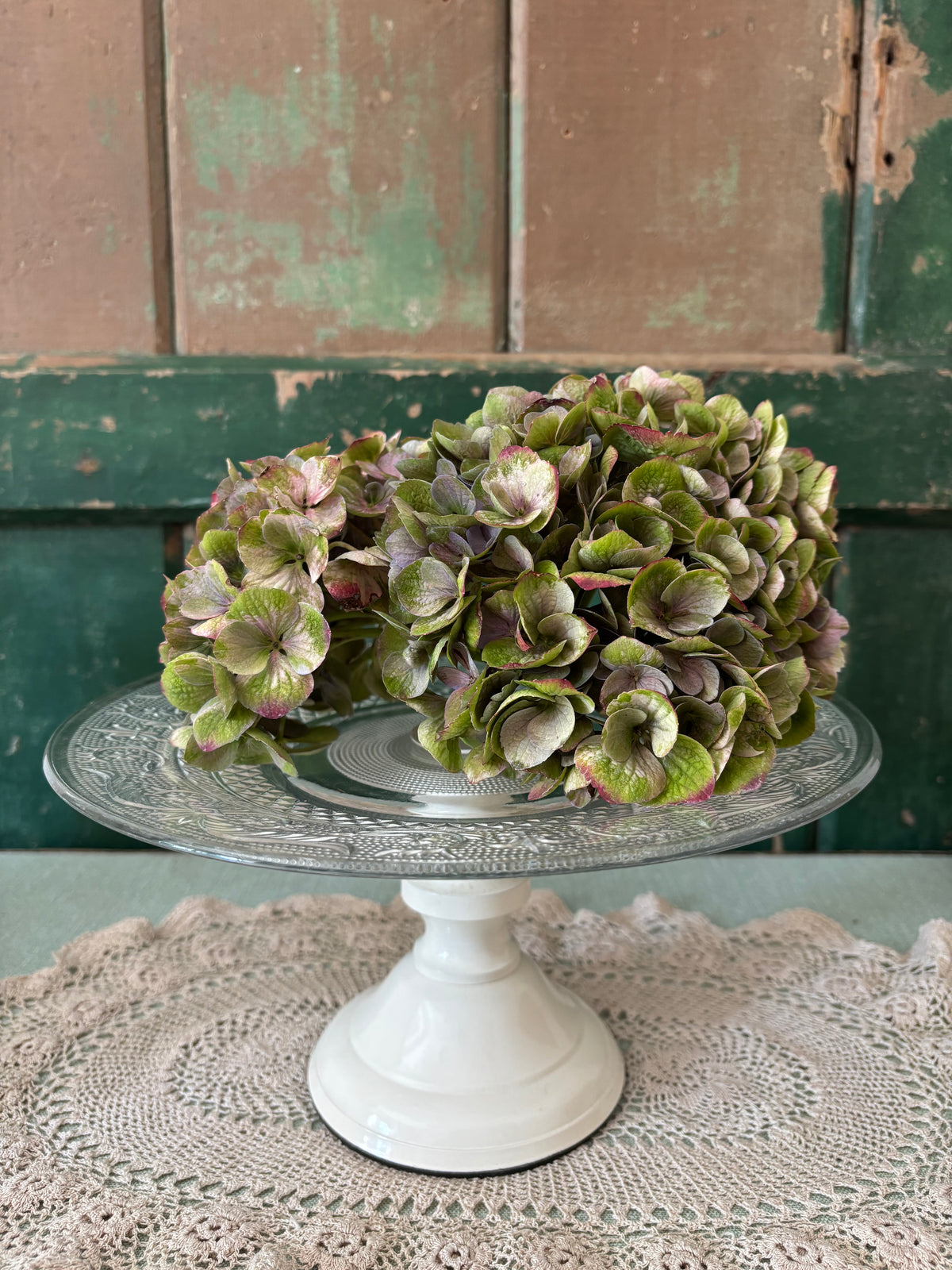 A  clear glass cake stand with a cream pedestal base.