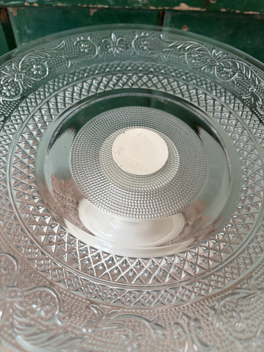 A close up of the top of a cake stand showing the pressed glass pattern.