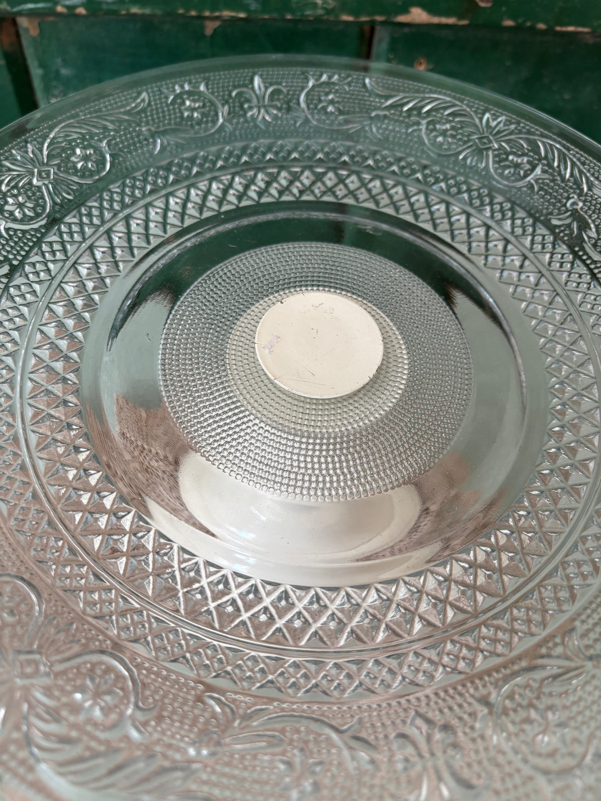 A close up of the top of a cake stand showing the pressed glass pattern.